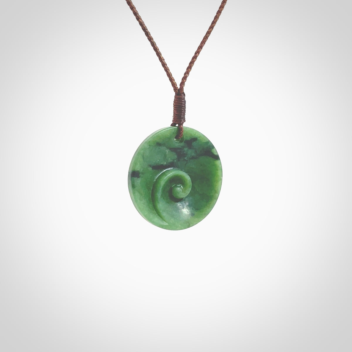 This pendant is a small sized and cupped koru necklace carved from a dark green piece of New Zealand Marsden Jade. Kyohei Noguchi carved this piece for us so the workmanship is outstanding. Handmade in New Zealand, a beautiful piece of jade jewellery. Provided with an adjustable brown cord and packaged in a woven kete pouch.