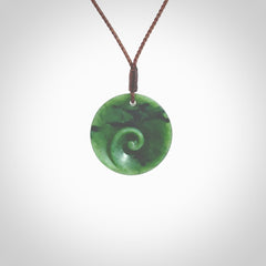 This pendant is a small sized and cupped koru necklace carved from a dark green piece of New Zealand Marsden Jade. Kyohei Noguchi carved this piece for us so the workmanship is outstanding. Handmade in New Zealand, a beautiful piece of jade jewellery. Provided with an adjustable brown cord and packaged in a woven kete pouch.