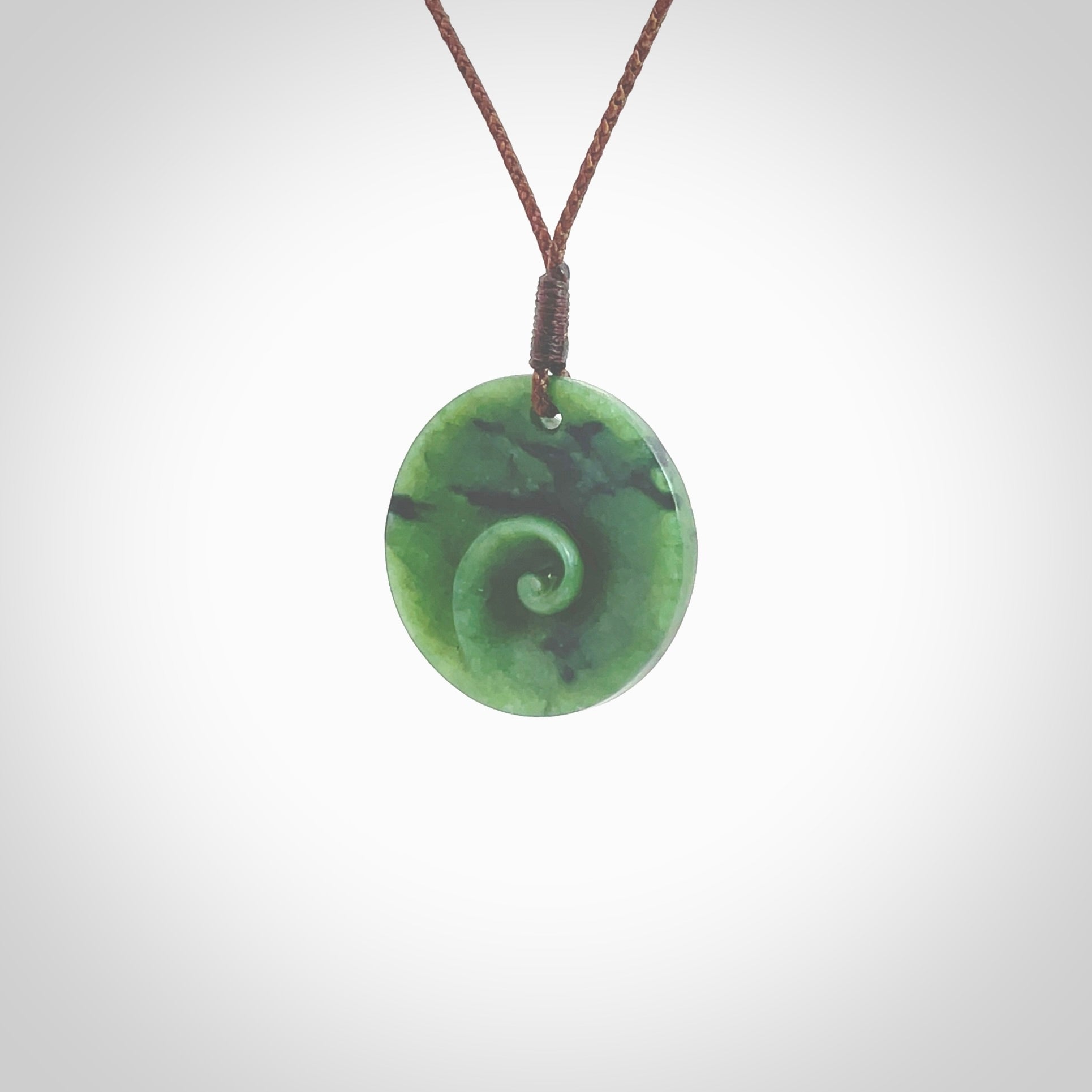 This pendant is a small sized and cupped koru necklace carved from a dark green piece of New Zealand Marsden Jade. Kyohei Noguchi carved this piece for us so the workmanship is outstanding. Handmade in New Zealand, a beautiful piece of jade jewellery. Provided with an adjustable brown cord and packaged in a woven kete pouch.