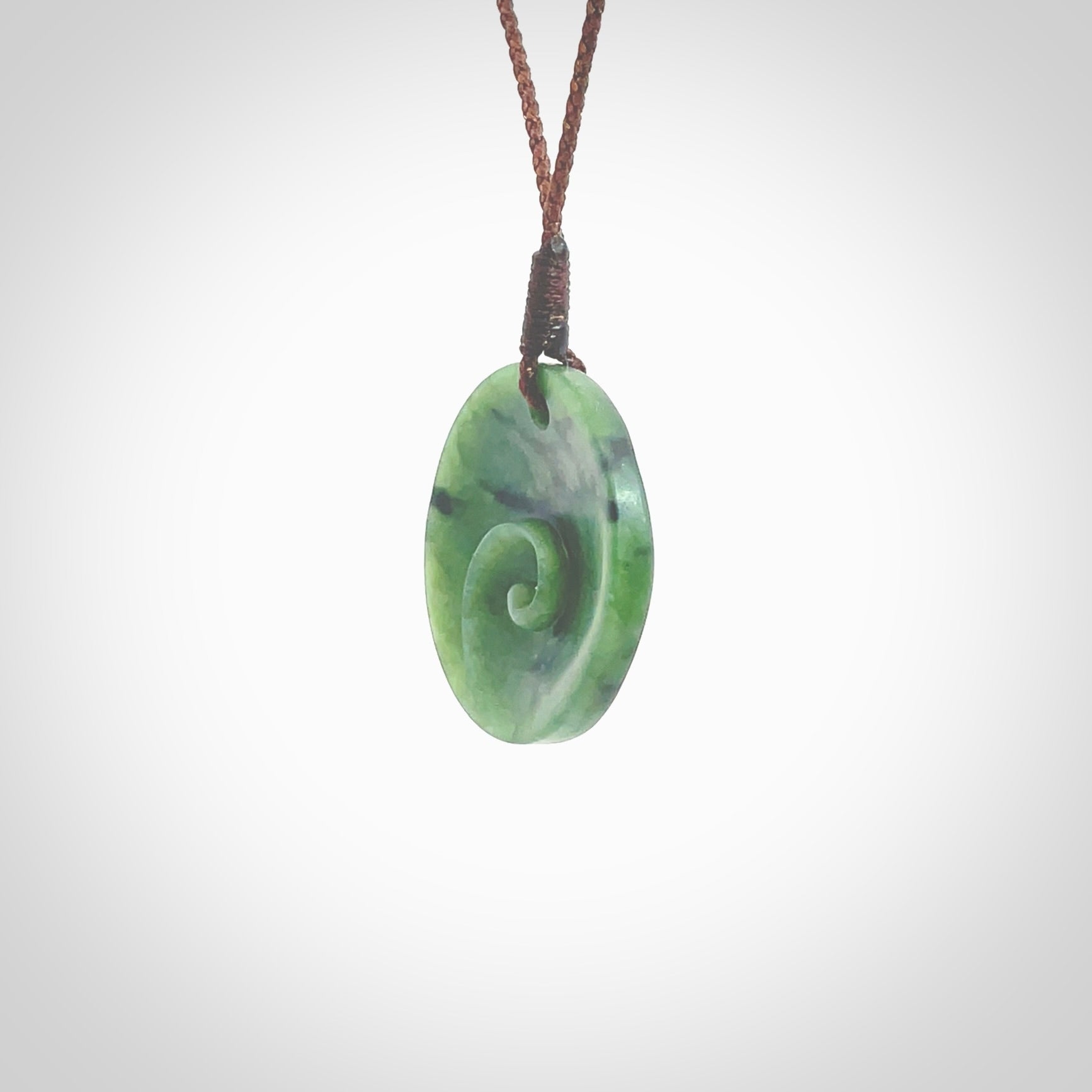 This pendant is a small sized and cupped koru necklace carved from a dark green piece of New Zealand Marsden Jade. Kyohei Noguchi carved this piece for us so the workmanship is outstanding. Handmade in New Zealand, a beautiful piece of jade jewellery. Provided with an adjustable brown cord and packaged in a woven kete pouch.