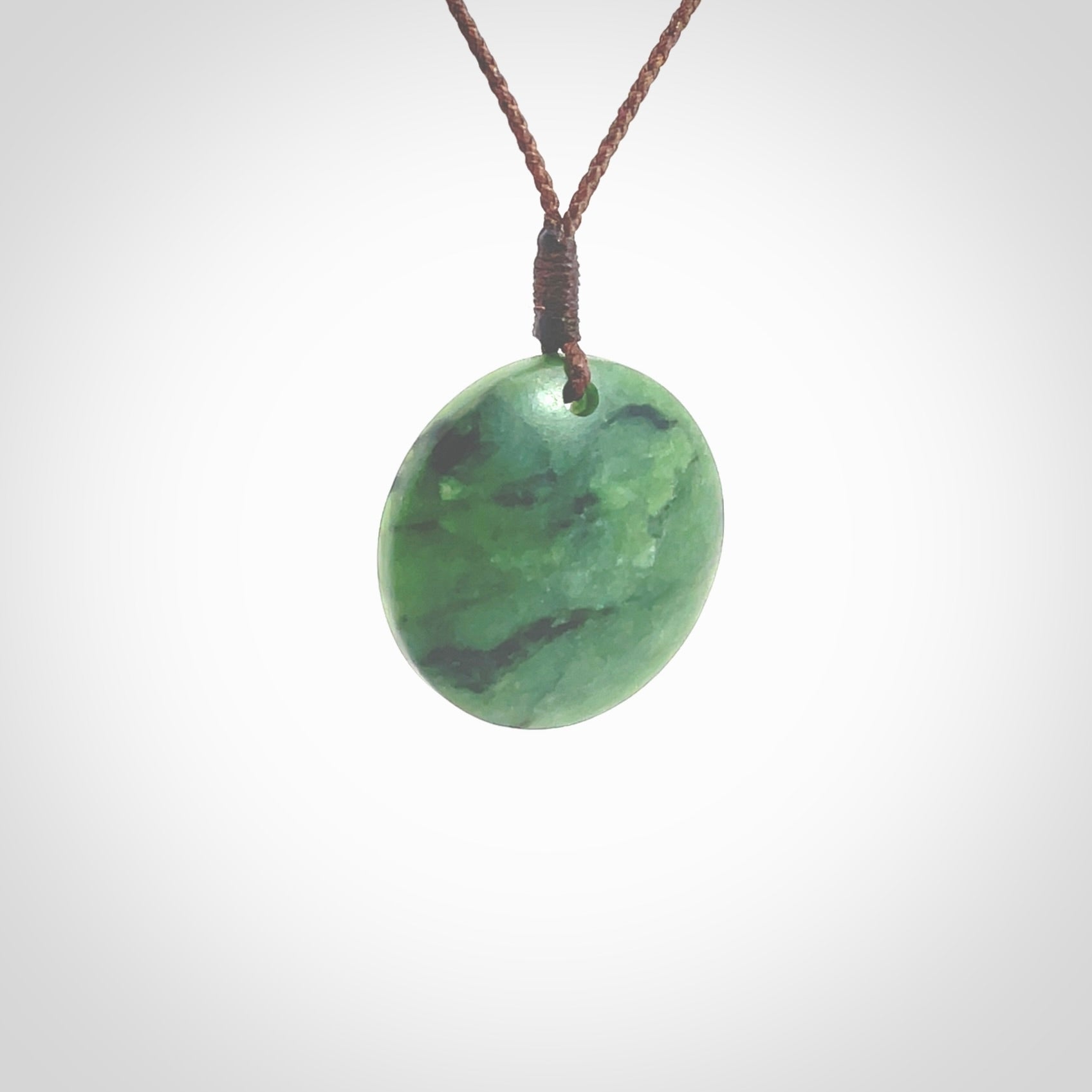 This pendant is a small sized and cupped koru necklace carved from a dark green piece of New Zealand Marsden Jade. Kyohei Noguchi carved this piece for us so the workmanship is outstanding. Handmade in New Zealand, a beautiful piece of jade jewellery. Provided with an adjustable brown cord and packaged in a woven kete pouch.