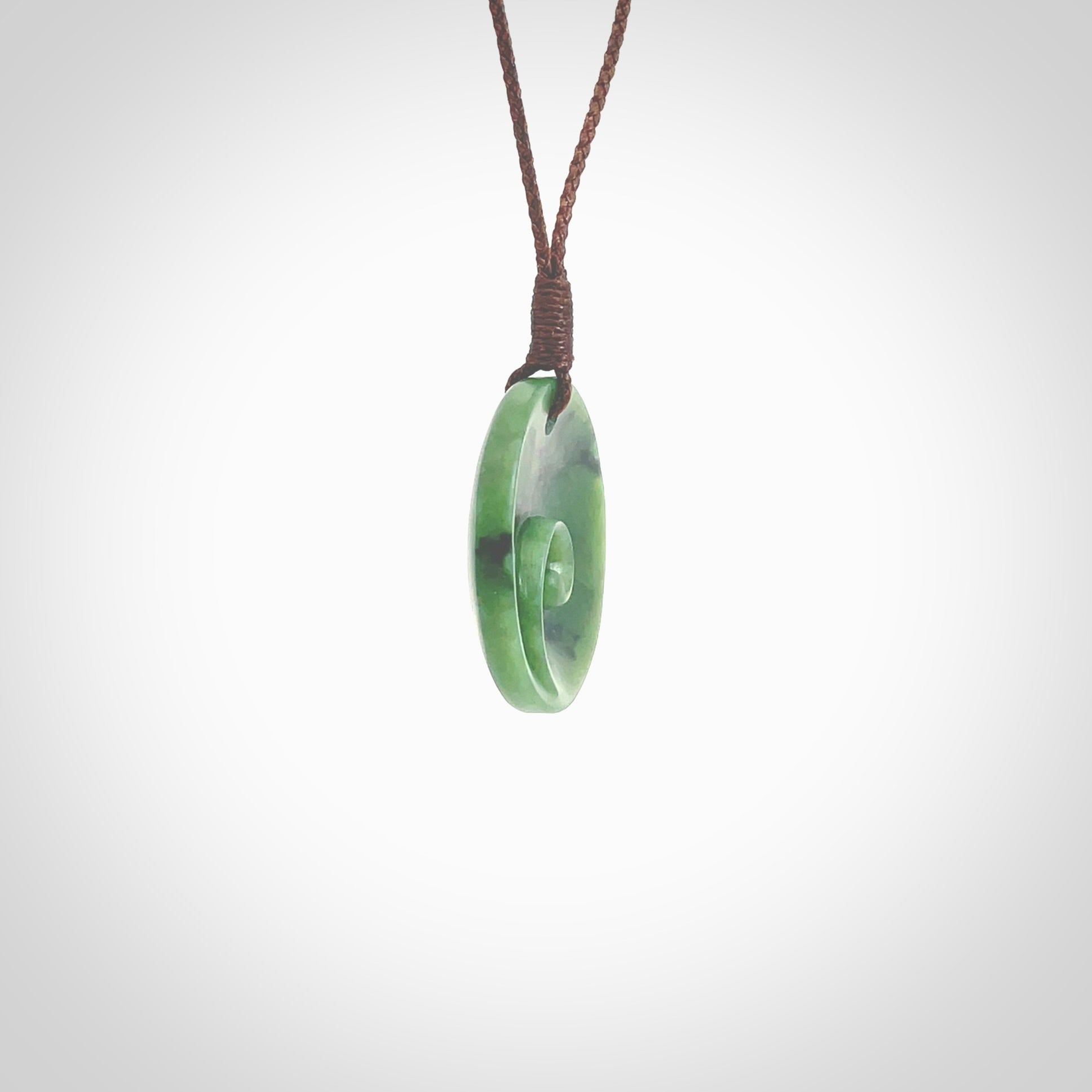 This pendant is a small sized and cupped koru necklace carved from a dark green piece of New Zealand Marsden Jade. Kyohei Noguchi carved this piece for us so the workmanship is outstanding. Handmade in New Zealand, a beautiful piece of jade jewellery. Provided with an adjustable brown cord and packaged in a woven kete pouch.