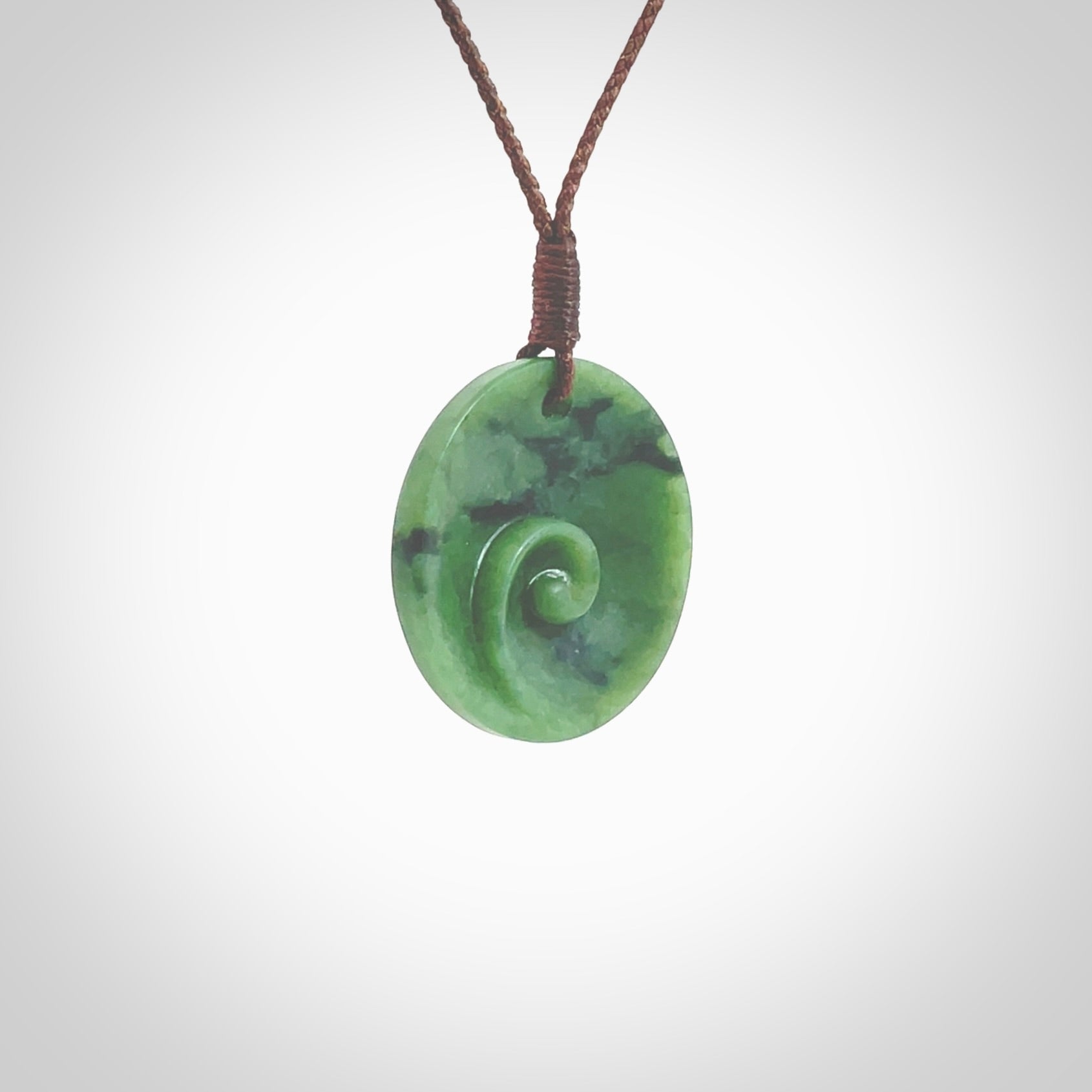 This pendant is a small sized and cupped koru necklace carved from a dark green piece of New Zealand Marsden Jade. Kyohei Noguchi carved this piece for us so the workmanship is outstanding. Handmade in New Zealand, a beautiful piece of jade jewellery. Provided with an adjustable brown cord and packaged in a woven kete pouch.