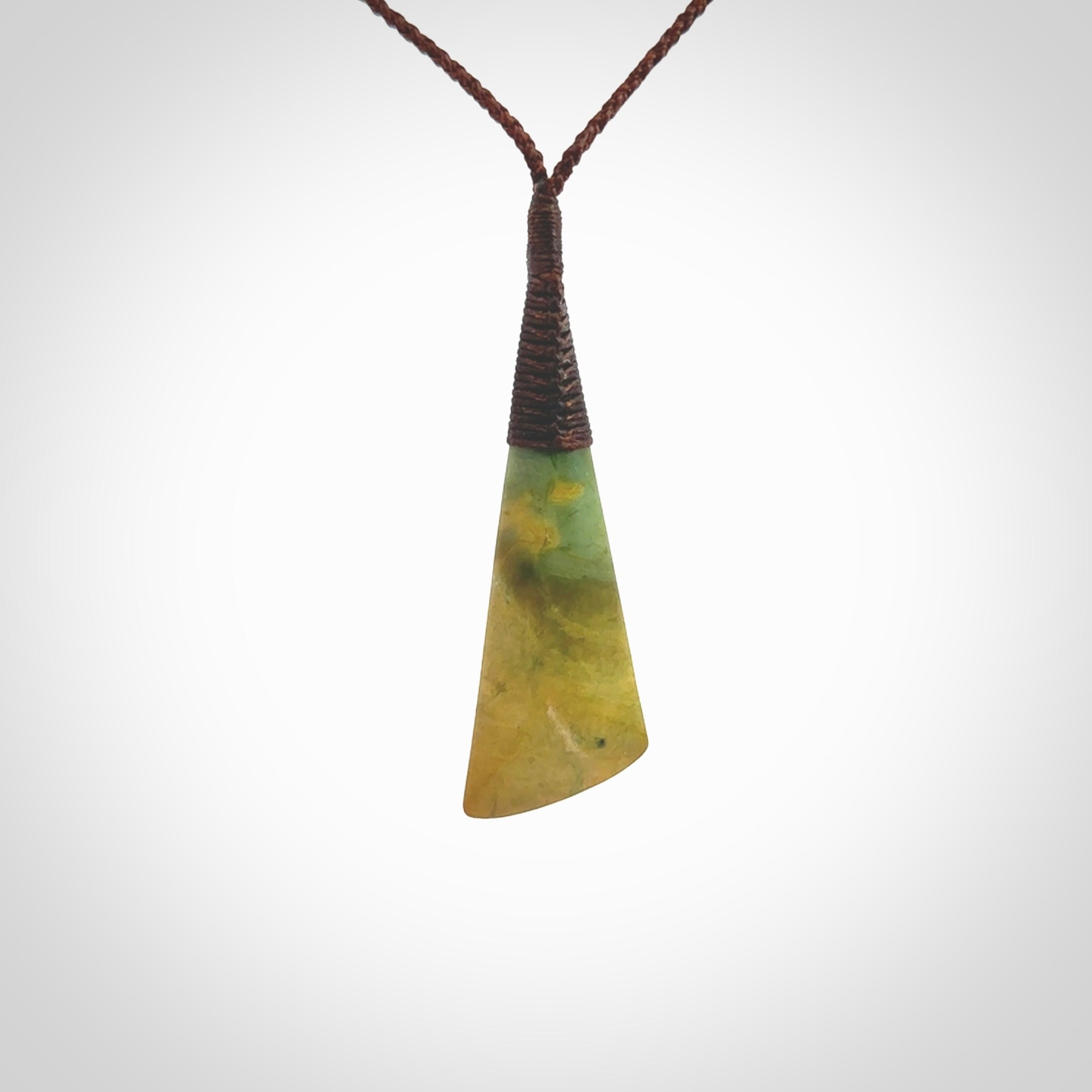 This photo shows a beautiful large sized flower jade drop. It is hand carved from a piece of New Zealand pounamu, with fascinating orange and green inclusions throughout the stone. We have this on a brown coloured, adjustable four plait cord. We ship this worldwide with an express courier service. Postage is free.