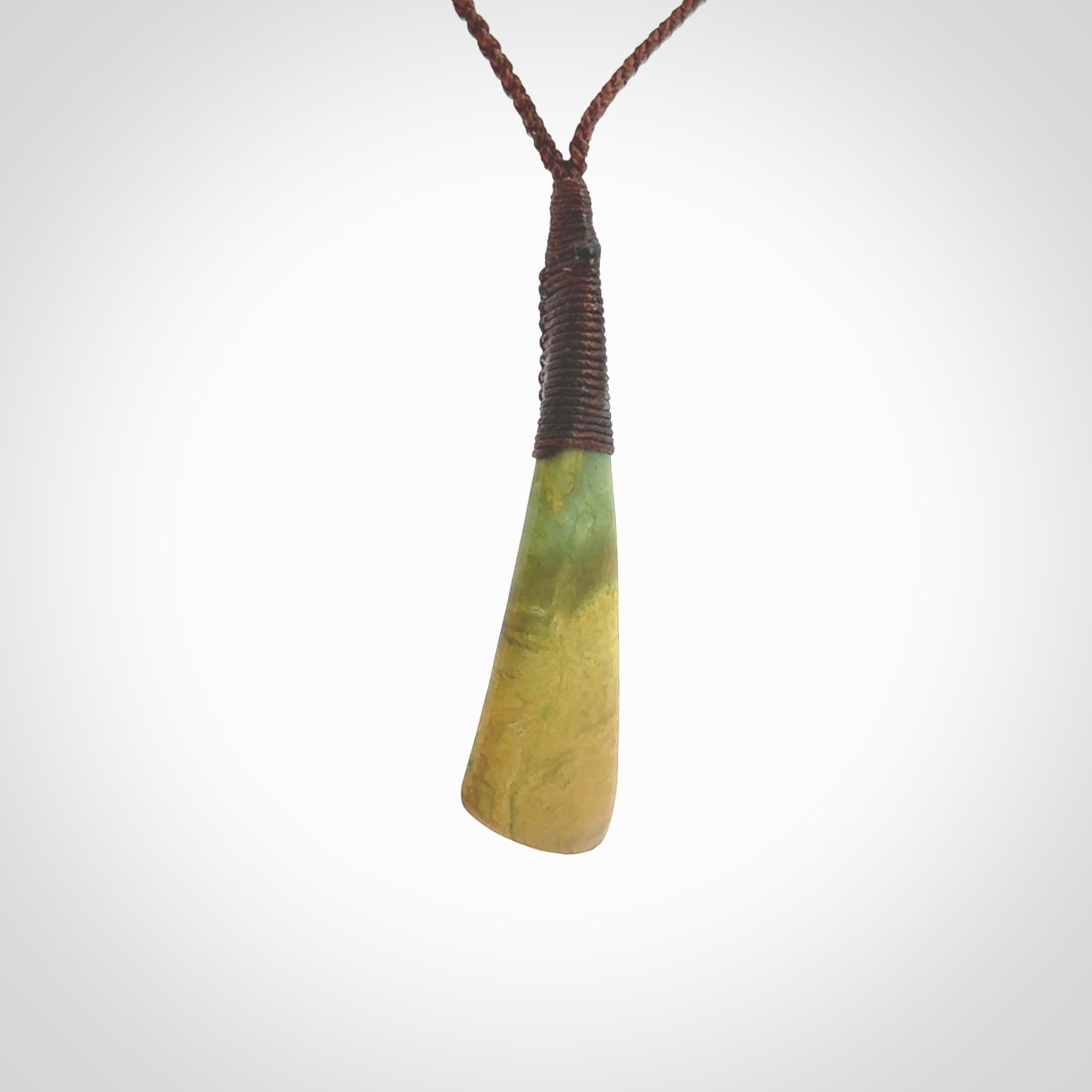 This photo shows a beautiful large sized flower jade drop. It is hand carved from a piece of New Zealand pounamu, with fascinating orange and green inclusions throughout the stone. We have this on a brown coloured, adjustable four plait cord. We ship this worldwide with an express courier service. Postage is free.