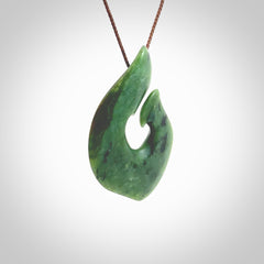 This photo shows a perfectly New Zealand jade hook pendant. It is hand carved from a deep green piece of New Zealand jade and is suspended on a brown four plait cord that is length adjustable. Hand carved Jade hook by Kyohei Noguchi.