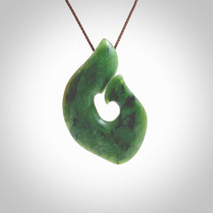 This photo shows a perfectly New Zealand jade hook pendant. It is hand carved from a deep green piece of New Zealand jade and is suspended on a brown four plait cord that is length adjustable. Hand carved Jade hook by Kyohei Noguchi.