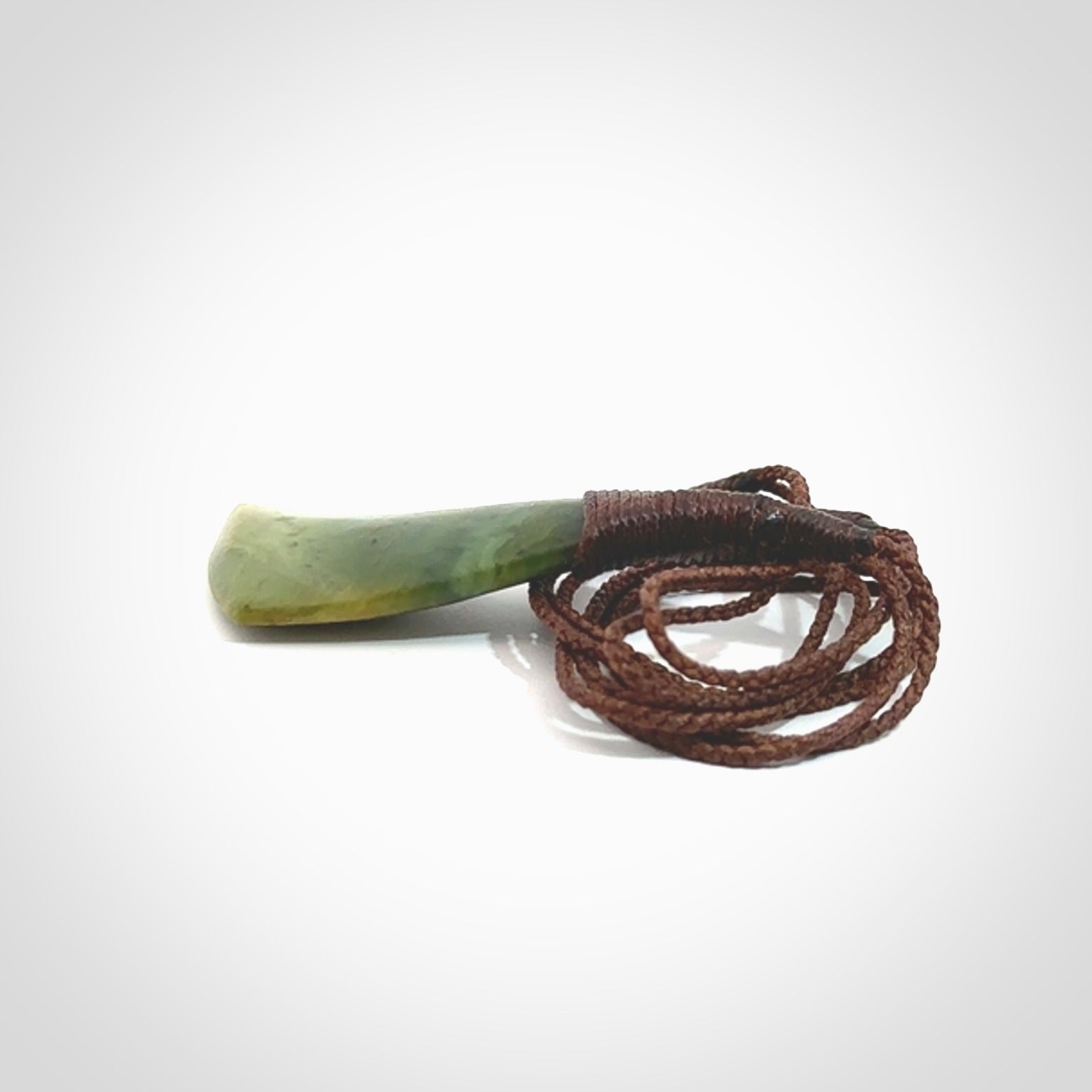 This photo shows a beautiful medium sized flower jade drop. It is hand carved from a piece of New Zealand pounamu, with fascinating orange and green inclusions throughout the stone. We have this on a brown coloured, adjustable four plait cord. We ship this worldwide with an express courier service. Postage is free.