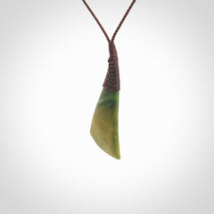 This photo shows a beautiful medium sized flower jade drop. It is hand carved from a piece of New Zealand pounamu, with fascinating orange and green inclusions throughout the stone. We have this on a brown coloured, adjustable four plait cord. We ship this worldwide with an express courier service. Postage is free.