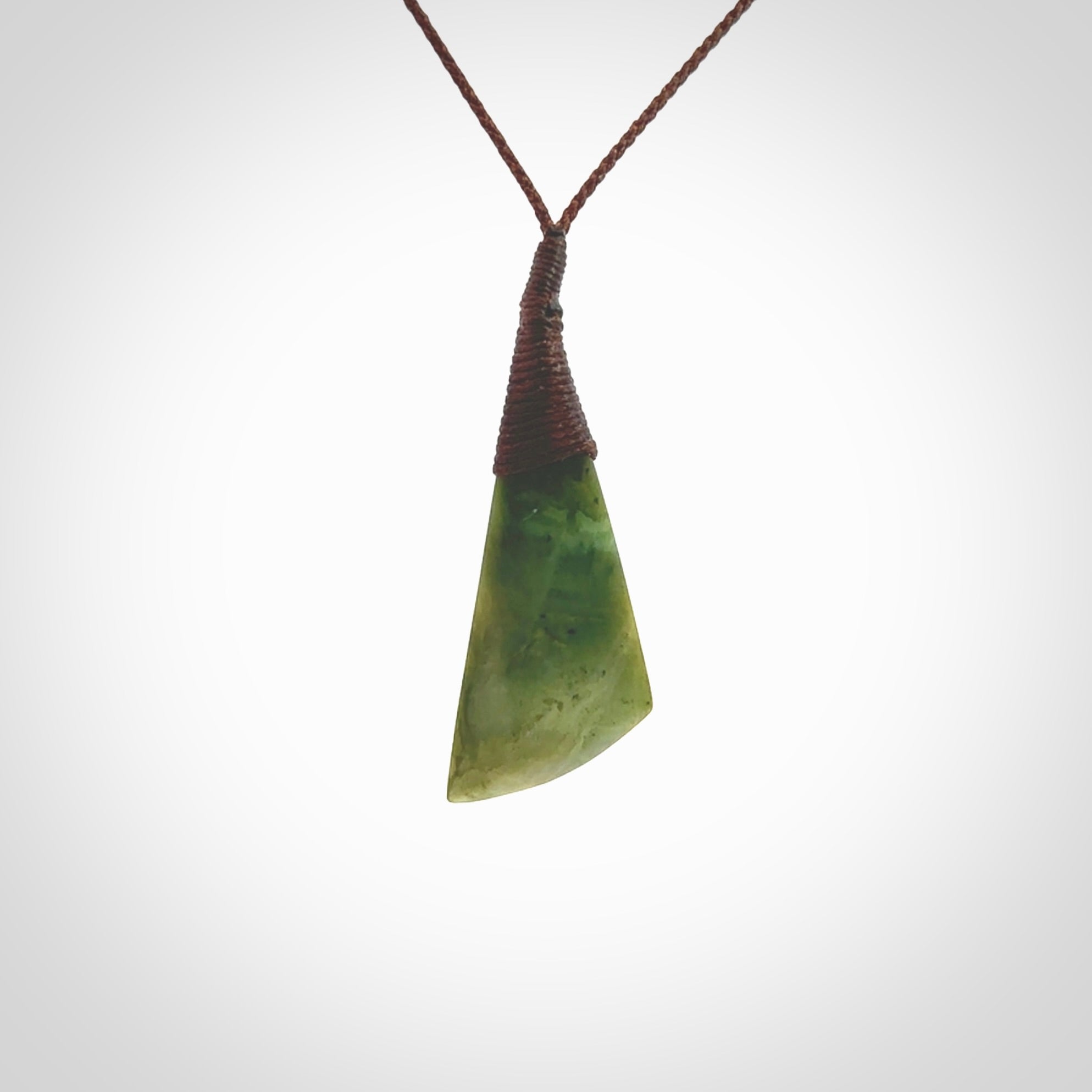 This photo shows a beautiful medium sized flower jade drop. It is hand carved from a piece of New Zealand pounamu, with fascinating orange and green inclusions throughout the stone. We have this on a brown coloured, adjustable four plait cord. We ship this worldwide with an express courier service. Postage is free.