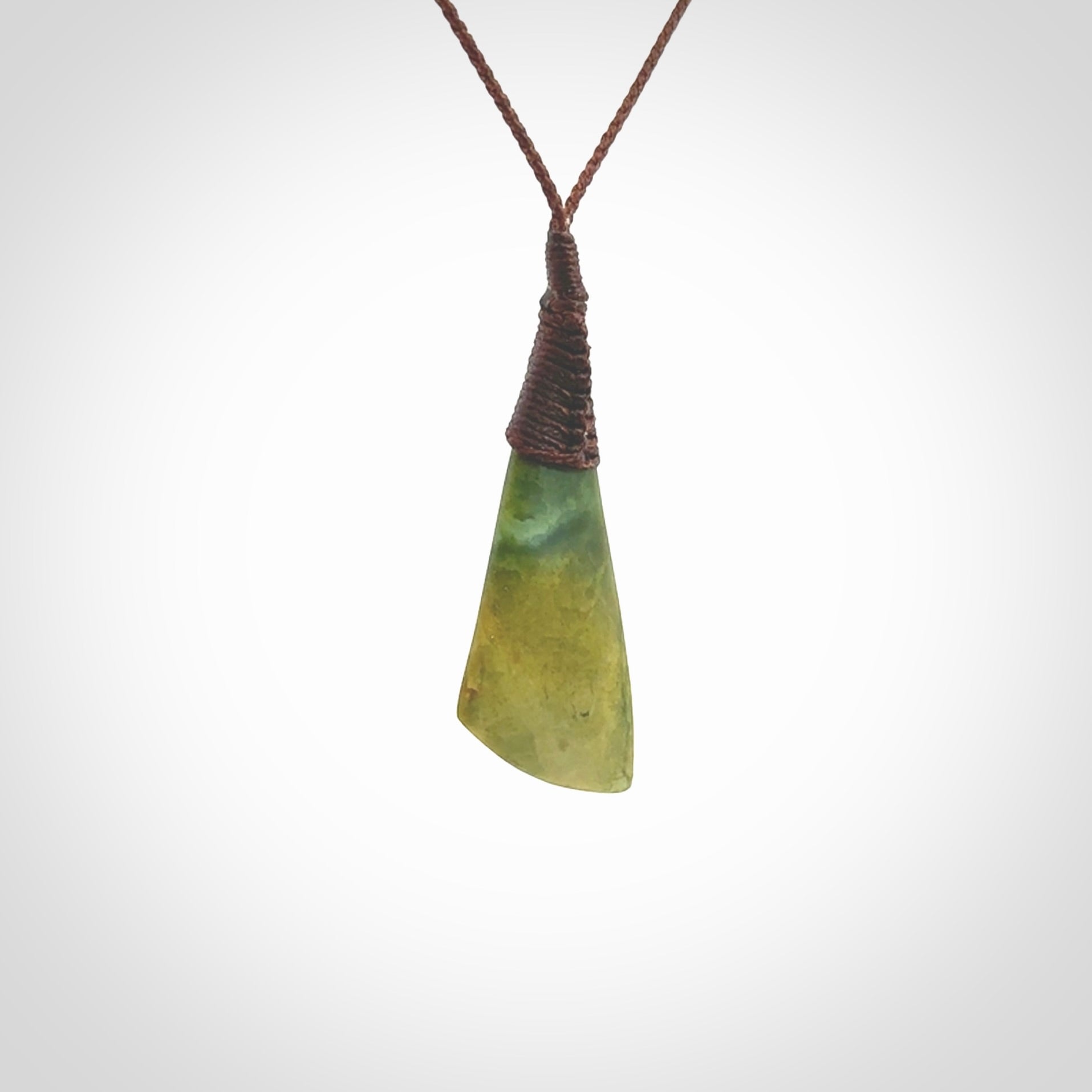 This photo shows a beautiful medium sized flower jade drop. It is hand carved from a piece of New Zealand pounamu, with fascinating orange and green inclusions throughout the stone. We have this on a brown coloured, adjustable four plait cord. We ship this worldwide with an express courier service. Postage is free.