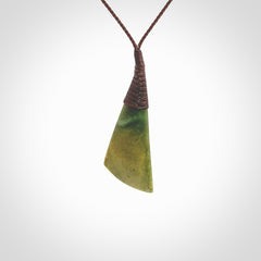 This photo shows a beautiful medium sized flower jade drop. It is hand carved from a piece of New Zealand pounamu, with fascinating orange and green inclusions throughout the stone. We have this on a brown coloured, adjustable four plait cord. We ship this worldwide with an express courier service. Postage is free.