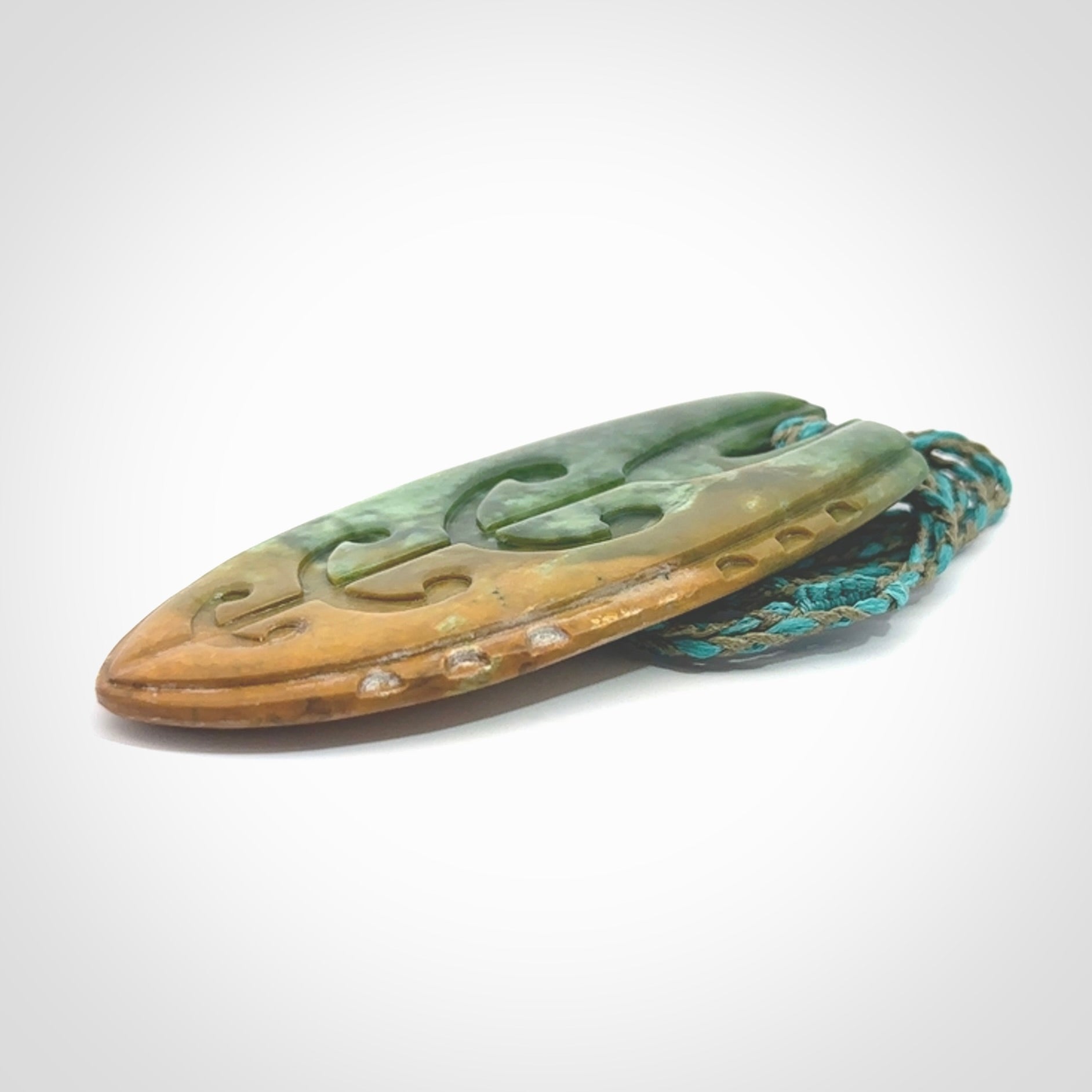 This photo shows a large Niho with koru carved into New Zealand Flower Jade. The artist, Kerry Thompson, has carved this beautifully. We have added a Mokohinau Blue/Sage Green adjustable cord. This is a fantastic work of art, we have one only.