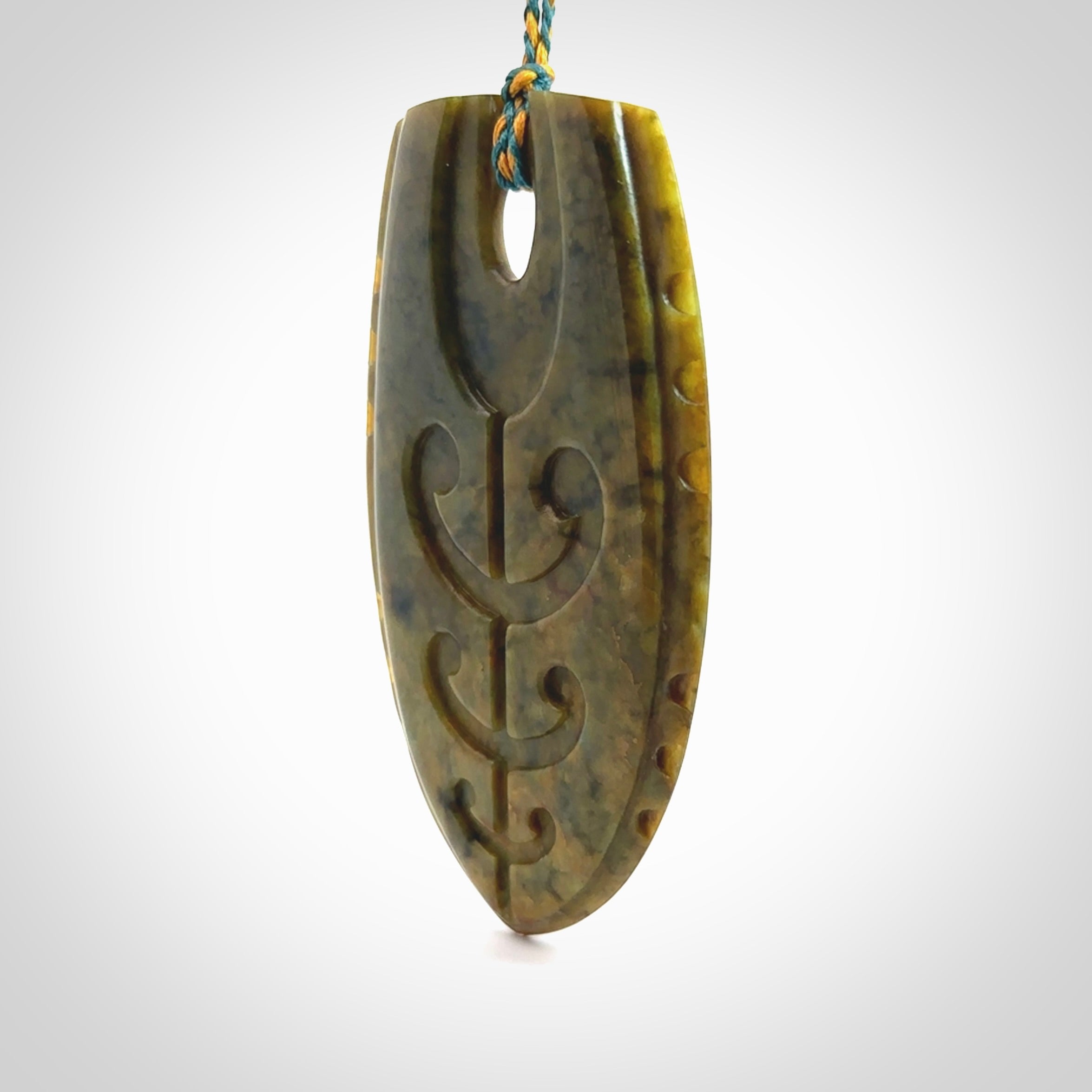 This photo shows a large Niho with koru carved into New Zealand Flower Jade. The artist, Kerry Thompson, has carved this beautifully. We have added a Sea Moss Blue/Harvest Gold adjustable cord. This is a fantastic work of art, we have one only.