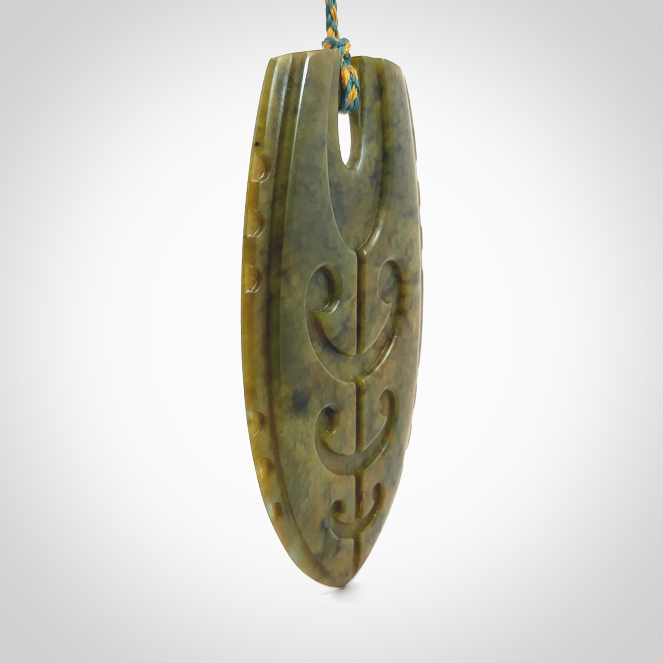 This photo shows a large Niho with koru carved into New Zealand Flower Jade. The artist, Kerry Thompson, has carved this beautifully. We have added a Sea Moss Blue/Harvest Gold adjustable cord. This is a fantastic work of art, we have one only.