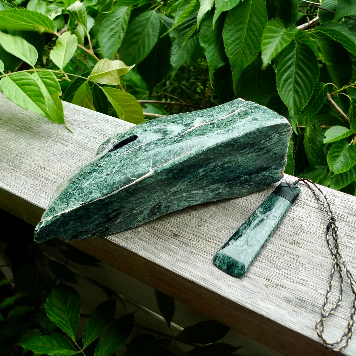 Large New Zealand Tangiwai Pounamu Toki pendant with Tangiwai boulder display case. Hand carved from a lovely piece of local New Zealand Tangiwai Stone. The quality of the workmanship and design is outstanding - this is a piece you will want to wear all the time. We have suspended this from an adjustable 3-plait tan/black cord.