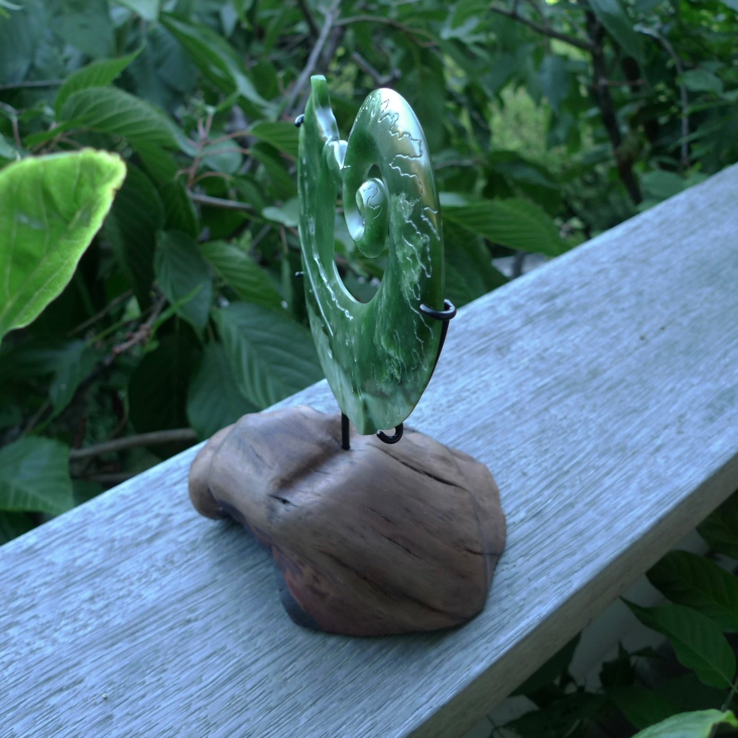 A photo of a New Zealand Jade whale tail in a wave sculpture with Rata Burr stand. This is a statement piece - hand crafted here in New Zealand by Ana Krakosky. Unique Art to display. Gifts for all lovers of hand made sculptures.