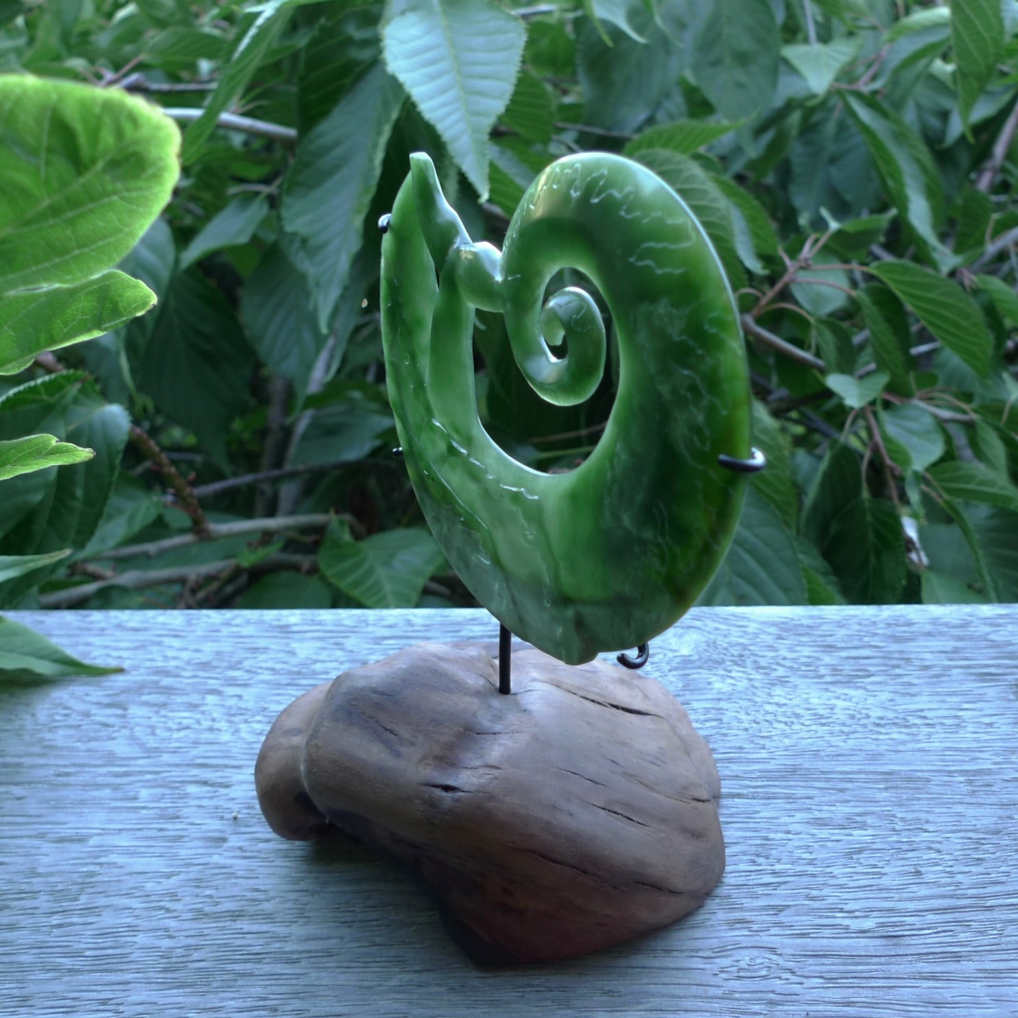 A photo of a New Zealand Jade whale tail in a wave sculpture with Rata Burr stand. This is a statement piece - hand crafted here in New Zealand by Ana Krakosky. Unique Art to display. Gifts for all lovers of hand made sculptures.