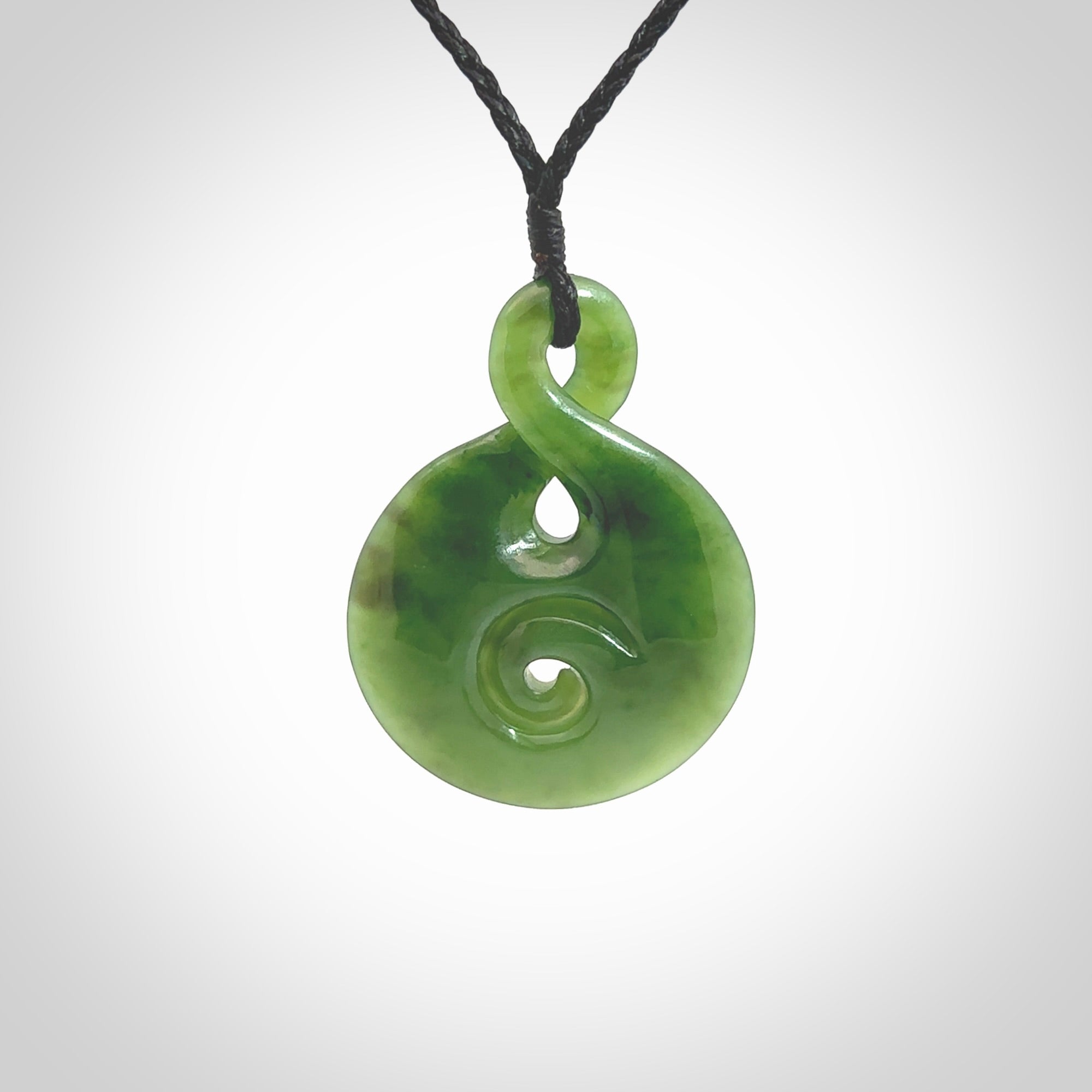 New Zealand Jade twist with koru pendant. Hand carved from rare New Zealand jade this is a beautiful pounamu pendant. The cord is hand plaited and is length adjustable. A very beautiful greenstone pendant. For sale online by NZ Pacific.