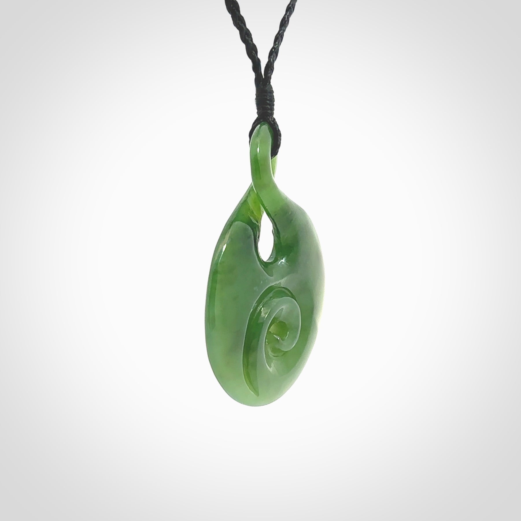 New Zealand Jade twist with koru pendant. Hand carved from rare New Zealand jade this is a beautiful pounamu pendant. The cord is hand plaited and is length adjustable. A very beautiful greenstone pendant. For sale online by NZ Pacific.