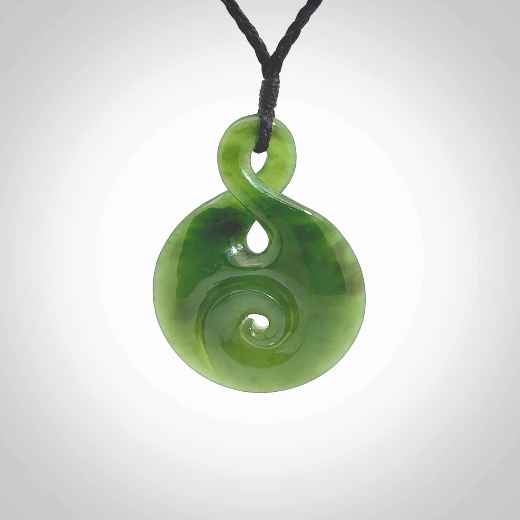 New Zealand Jade twist with koru pendant. Hand carved from rare New Zealand jade this is a beautiful pounamu pendant. The cord is hand plaited and is length adjustable. A very beautiful greenstone pendant. For sale online by NZ Pacific.