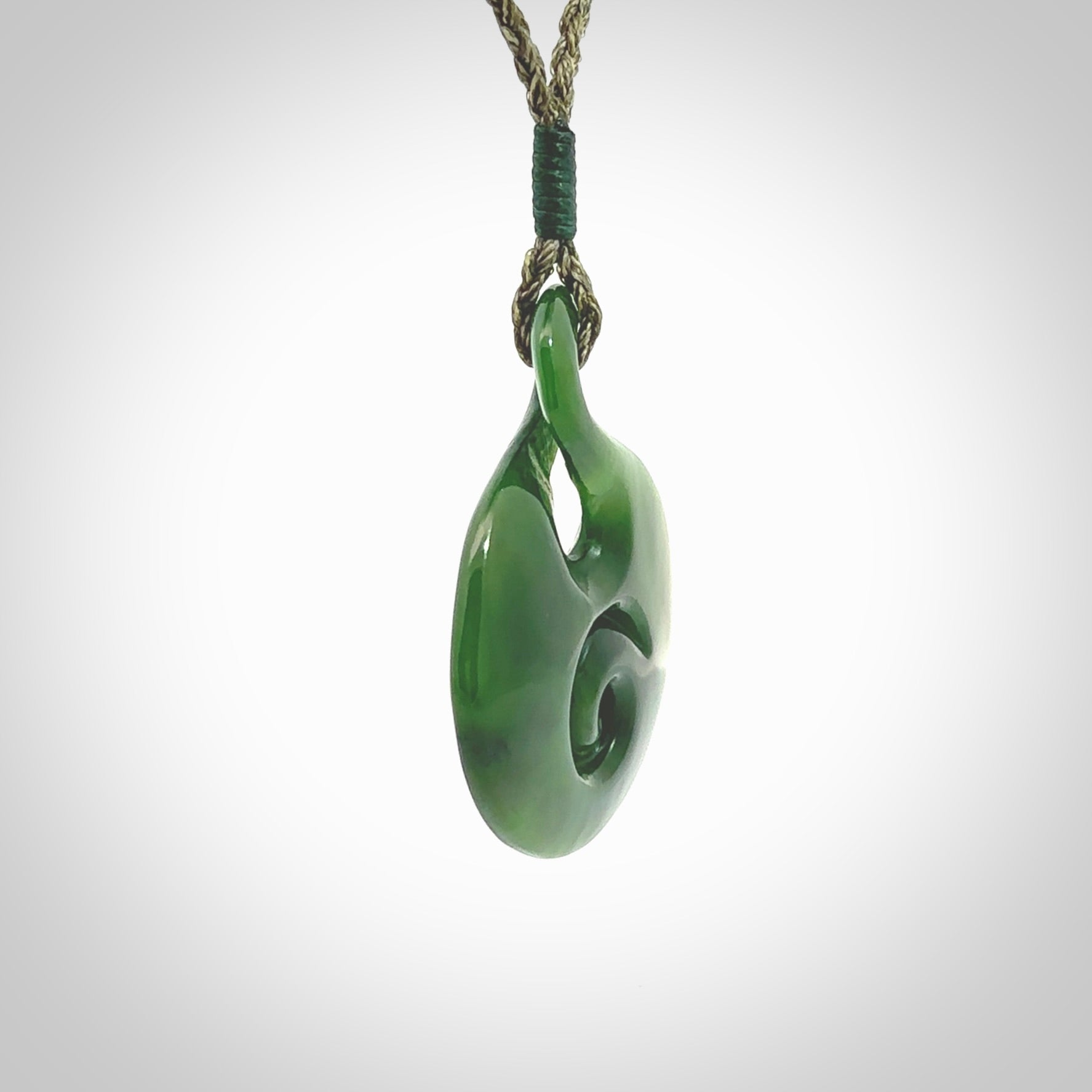 New Zealand Jade twist with koru pendant. Hand carved from rare New Zealand jade this is a beautiful pounamu pendant. The cord is hand plaited and is length adjustable. A very beautiful greenstone pendant. For sale online by NZ Pacific.