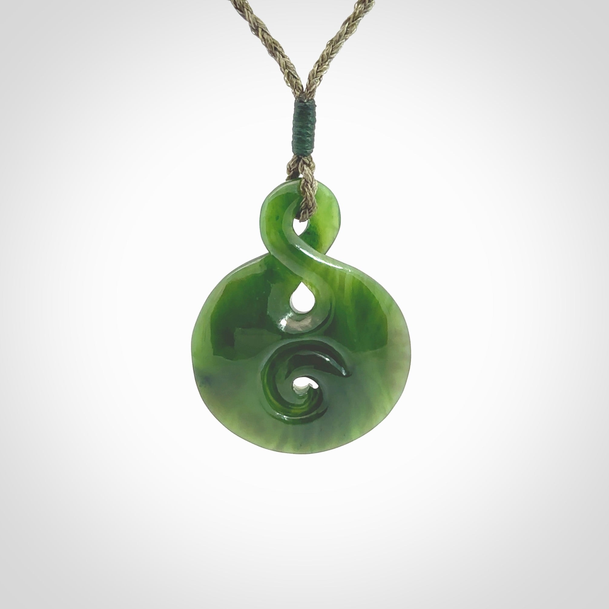 New Zealand Jade twist with koru pendant. Hand carved from rare New Zealand jade this is a beautiful pounamu pendant. The cord is hand plaited and is length adjustable. A very beautiful greenstone pendant. For sale online by NZ Pacific.