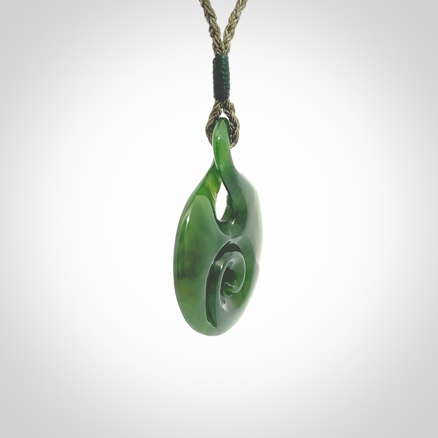 New Zealand Jade twist with koru pendant. Hand carved from rare New Zealand jade this is a beautiful pounamu pendant. The cord is hand plaited and is length adjustable. A very beautiful greenstone pendant. For sale online by NZ Pacific.