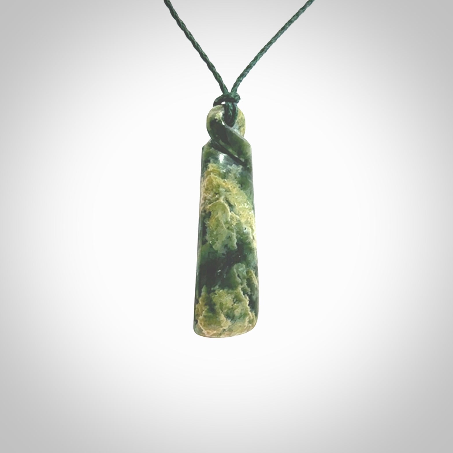 This pendant is a New Zealand jade single twist. It is hand carved from New Zealand Pounamu and has a mix of green, mint and pale colours interspersed throughout the stone. It has a fine twist, small and light. The cord is hand plaited and can be adjusted.