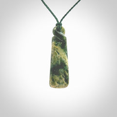 This pendant is a New Zealand jade single twist. It is hand carved from New Zealand Pounamu and has a mix of green, mint and pale colours interspersed throughout the stone. It has a fine twist, small and light. The cord is hand plaited and can be adjusted.