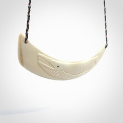 This photo shows a pendant we carved from boars tusk. It is a Blue Whale carved lengthwise into the tusk. This piece is suspended from a hand plaited necklace cord in Black and Pink. This pendant is 100% hand made.