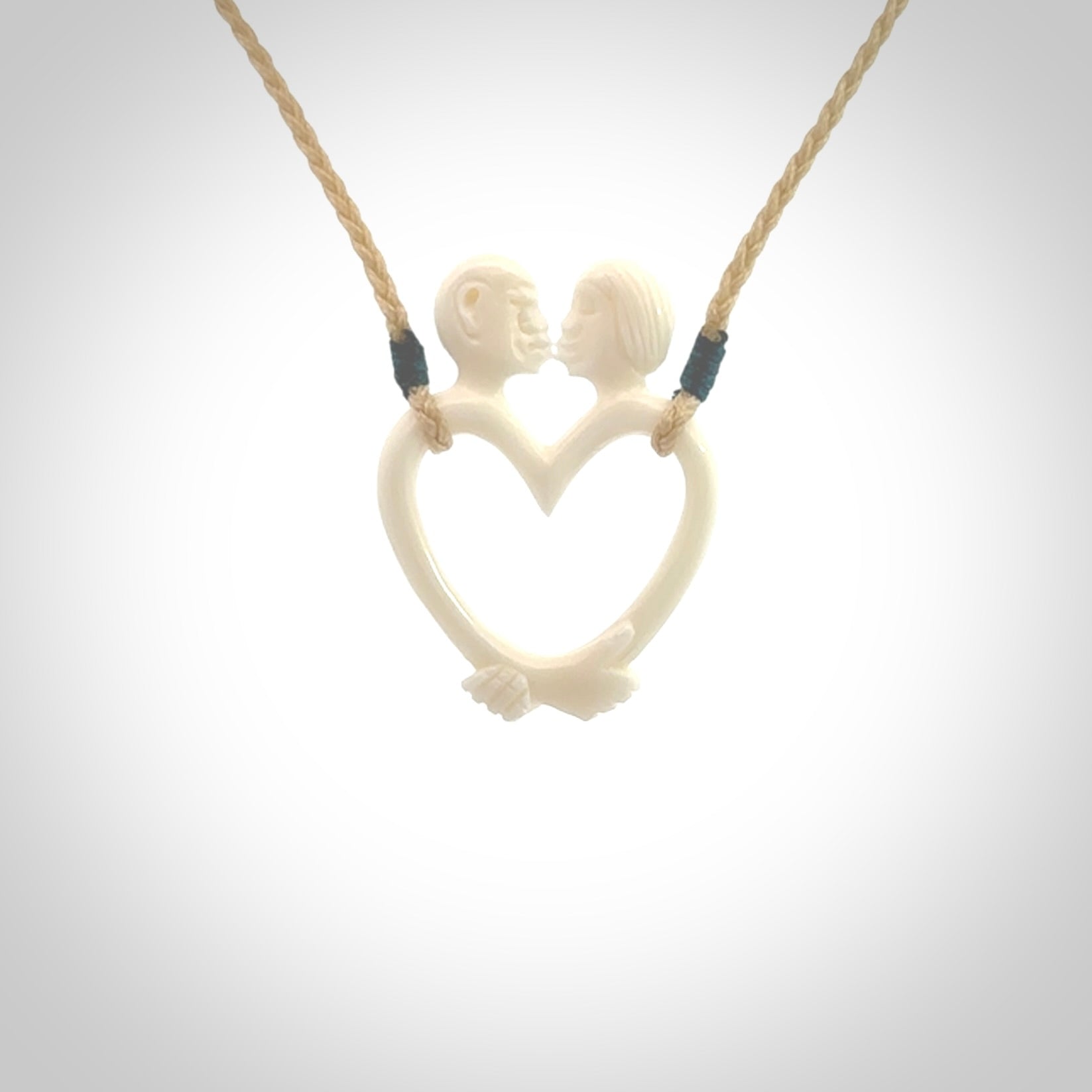 Hand carved bone couples kissing in the shape of a heart pendant. Contemporary design is bone. Pendants for lovers. Provided with adjustable cord.