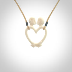 Hand carved bone couples kissing in the shape of a heart pendant. Contemporary design is bone. Pendants for lovers. Provided with adjustable cord.