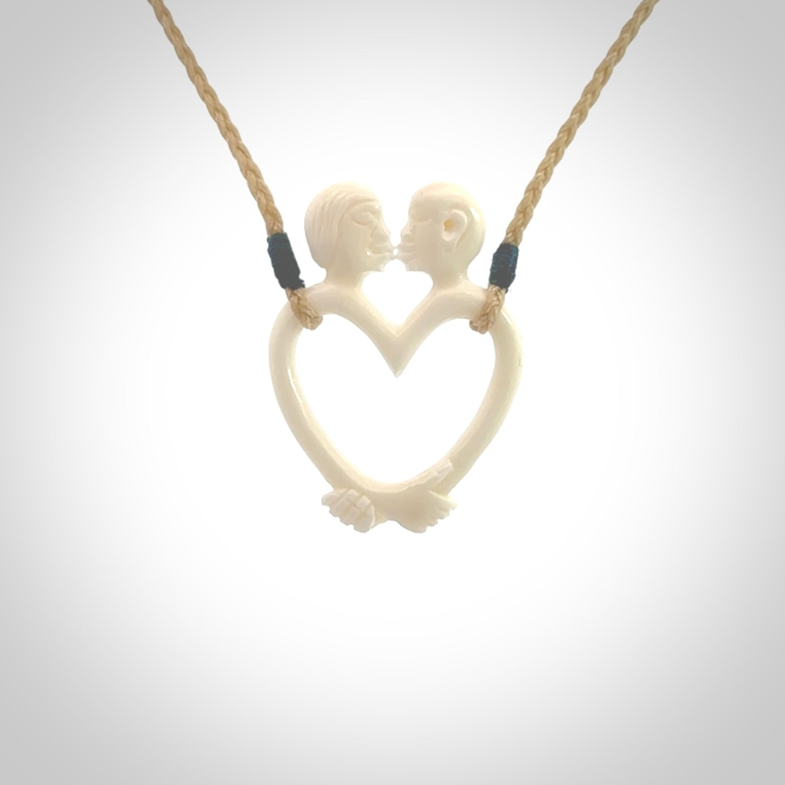 Hand carved bone couples kissing in the shape of a heart pendant. Contemporary design is bone. Pendants for lovers. Provided with adjustable cord.