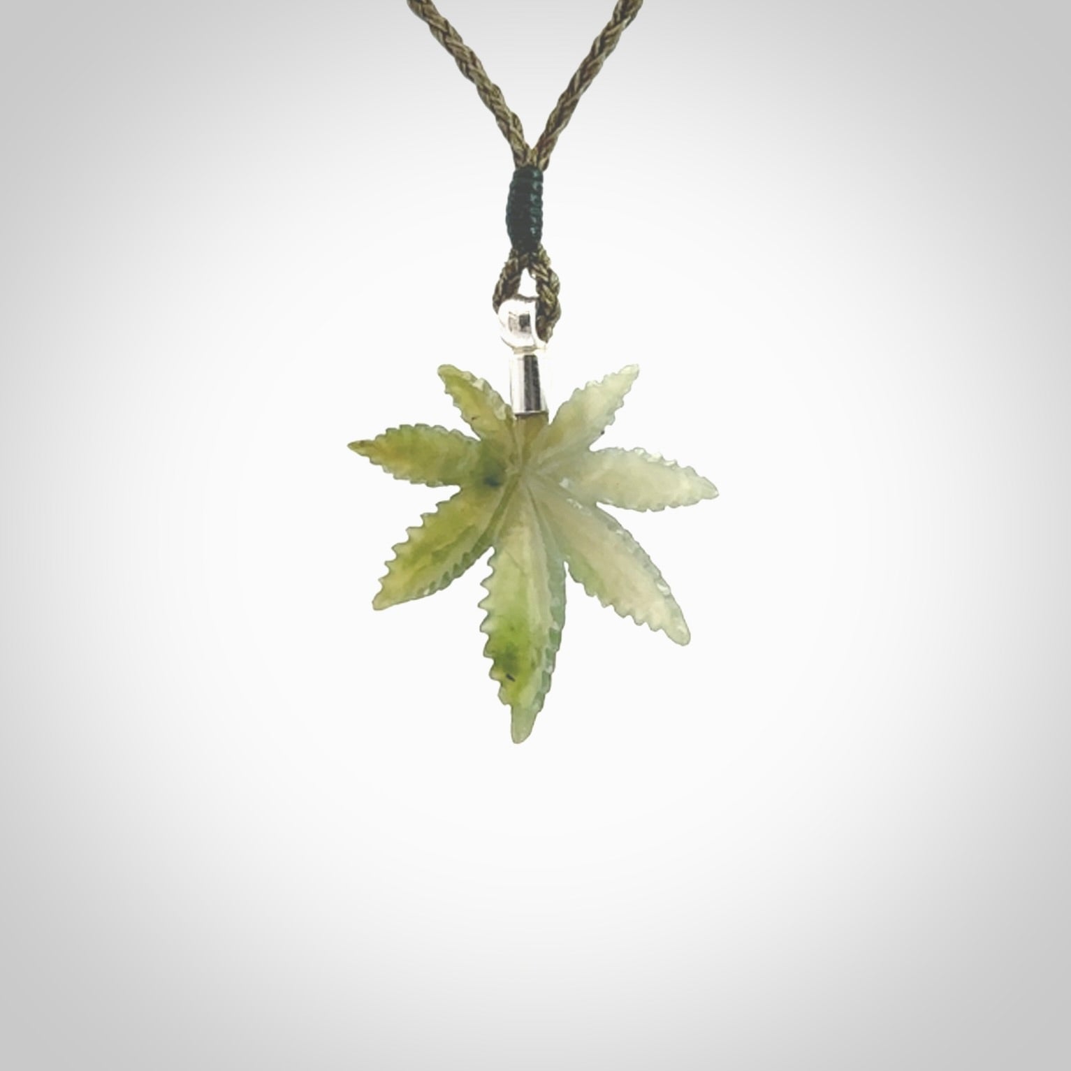 Cannabis Leaf Jade pendant with Sterling Silver Cap. Handmade jade Cannabis leaf jewellery made by NZ Pacific and for sale online. Jade Marijuana leaf pendant for men and women. Unique art to wear from NZ Pacific. Delivered on an adjustable Moss Green cord.