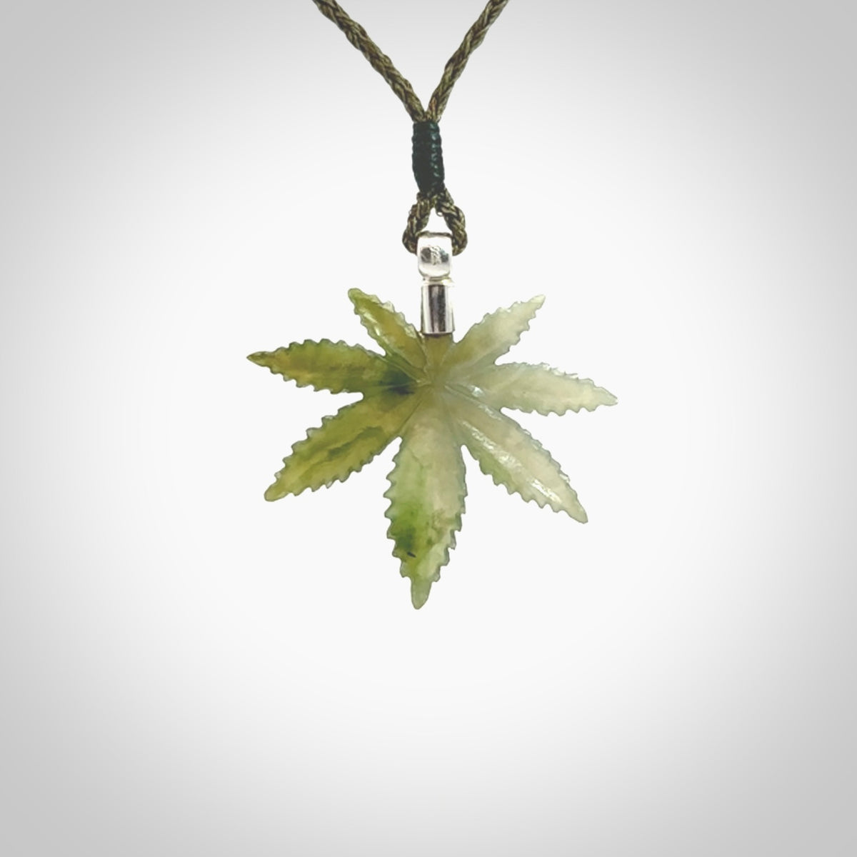 Cannabis Leaf Jade pendant with Sterling Silver Cap. Handmade jade Cannabis leaf jewellery made by NZ Pacific and for sale online. Jade Marijuana leaf pendant for men and women. Unique art to wear from NZ Pacific. Delivered on an adjustable Moss Green cord.