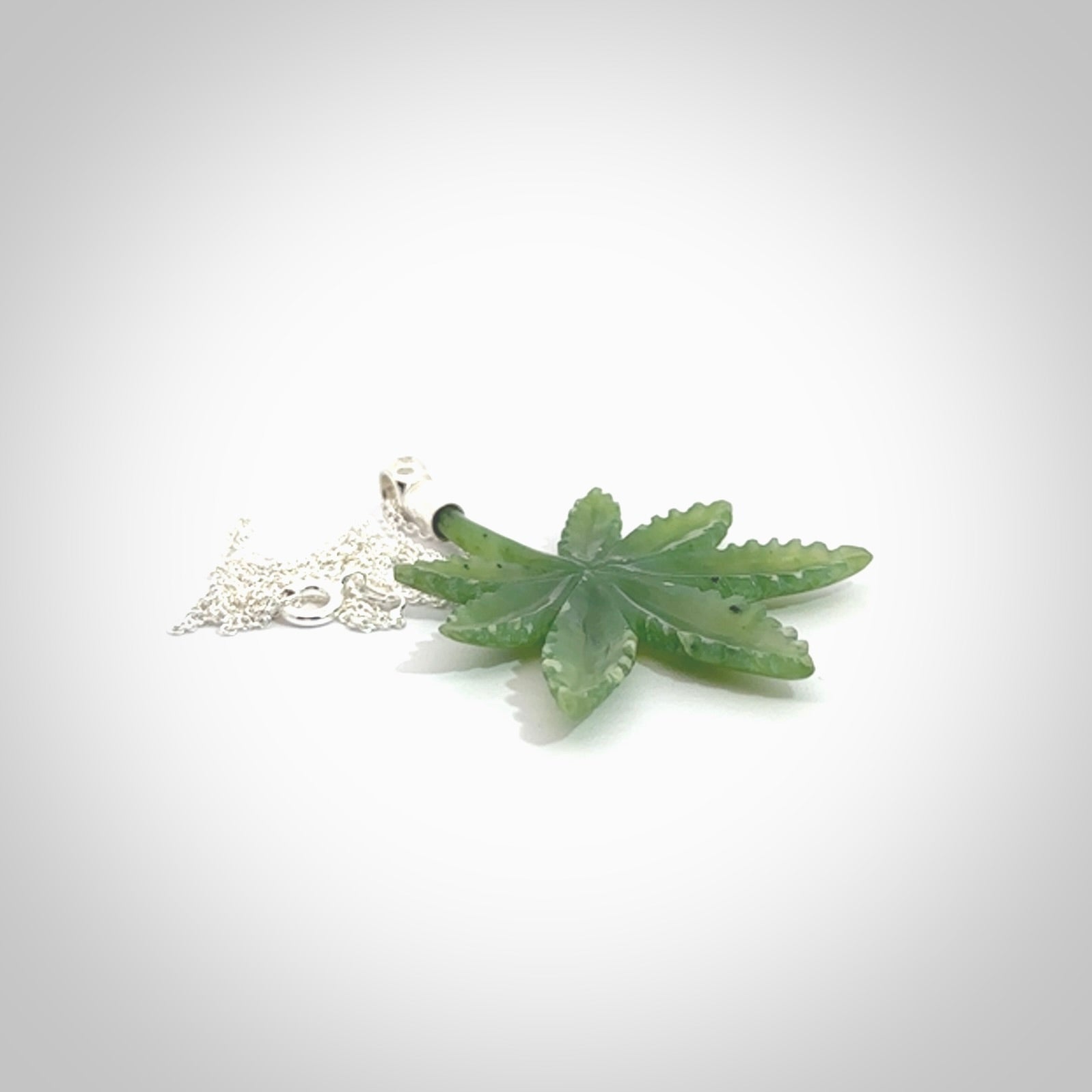 Cannabis Leaf Jade pendant with Sterling Silver Cap. Handmade jade Cannabis leaf jewellery made by NZ Pacific and for sale online. Jade Marijuana leaf pendant for men and women. Unique art to wear from NZ Pacific. Delivered on a Sterling Silver Chain.