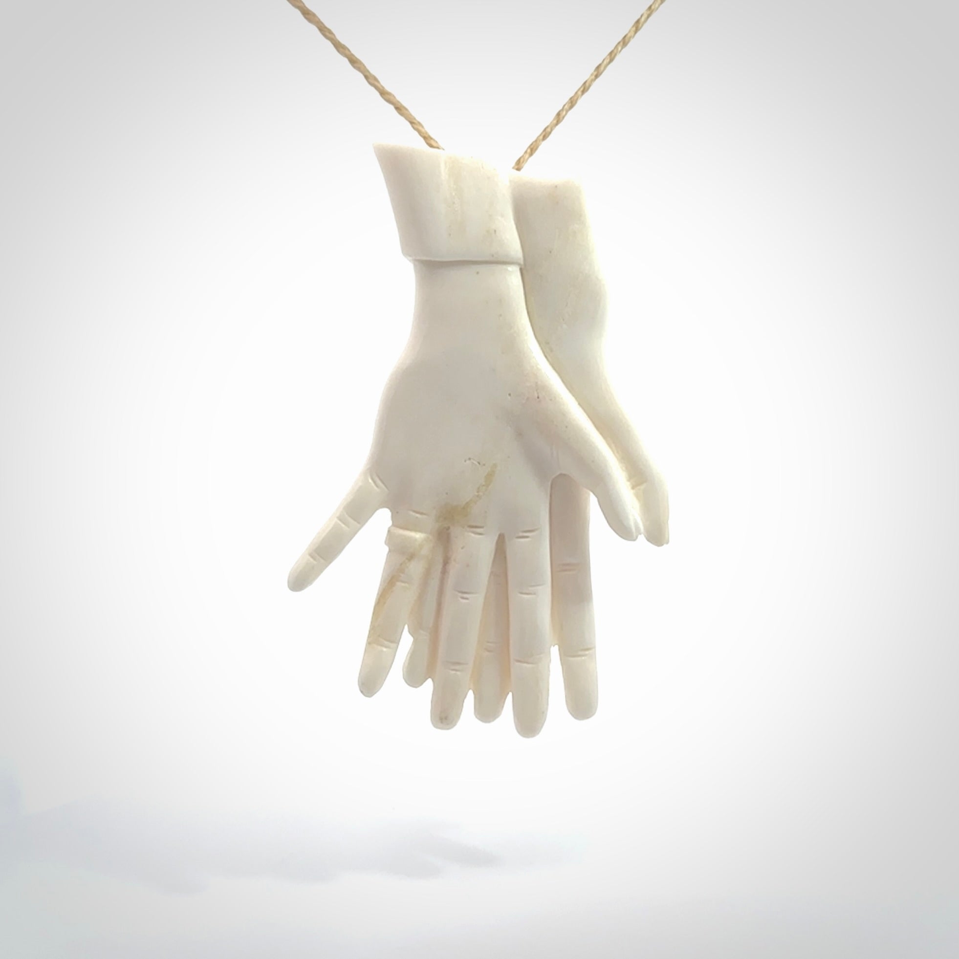 Hand carved large bone double hands with wedding rings pendant. A stunning work of art. This pendant is hand carved in bone and provided with an adjustable cord. A one off work of art to wear by NZ Pacific.