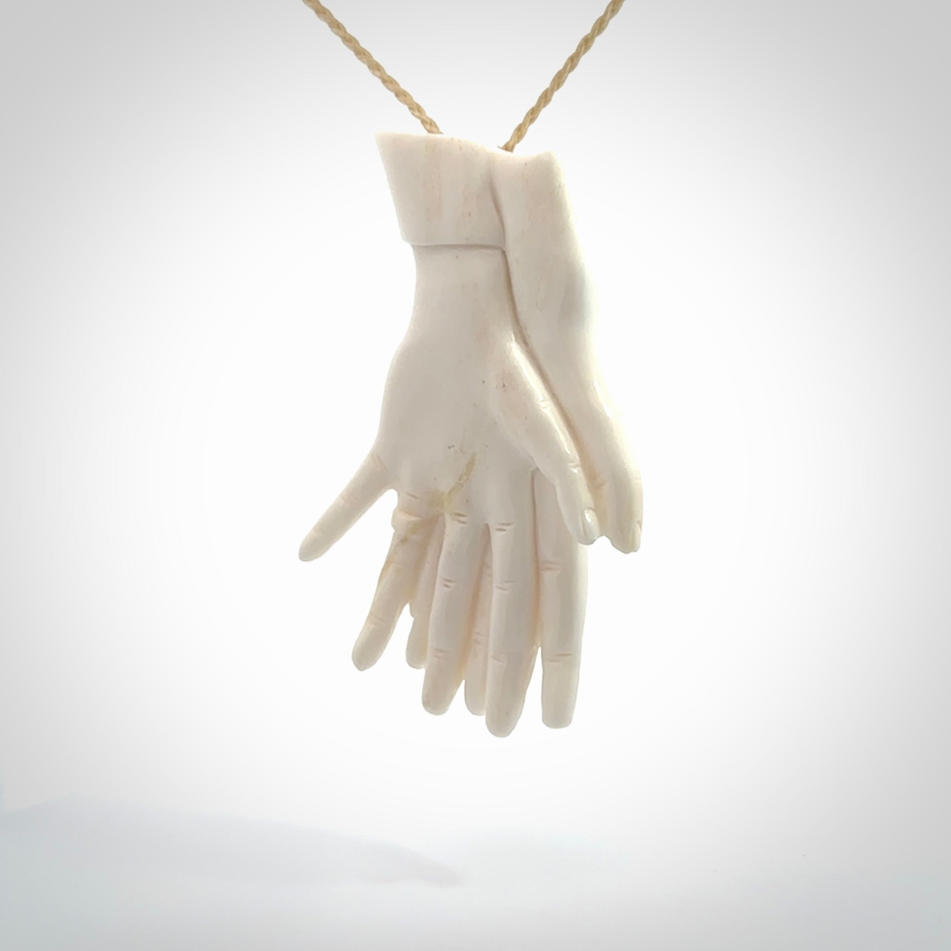 Hand carved large bone double hands with wedding rings pendant. A stunning work of art. This pendant is hand carved in bone and provided with an adjustable cord. A one off work of art to wear by NZ Pacific.