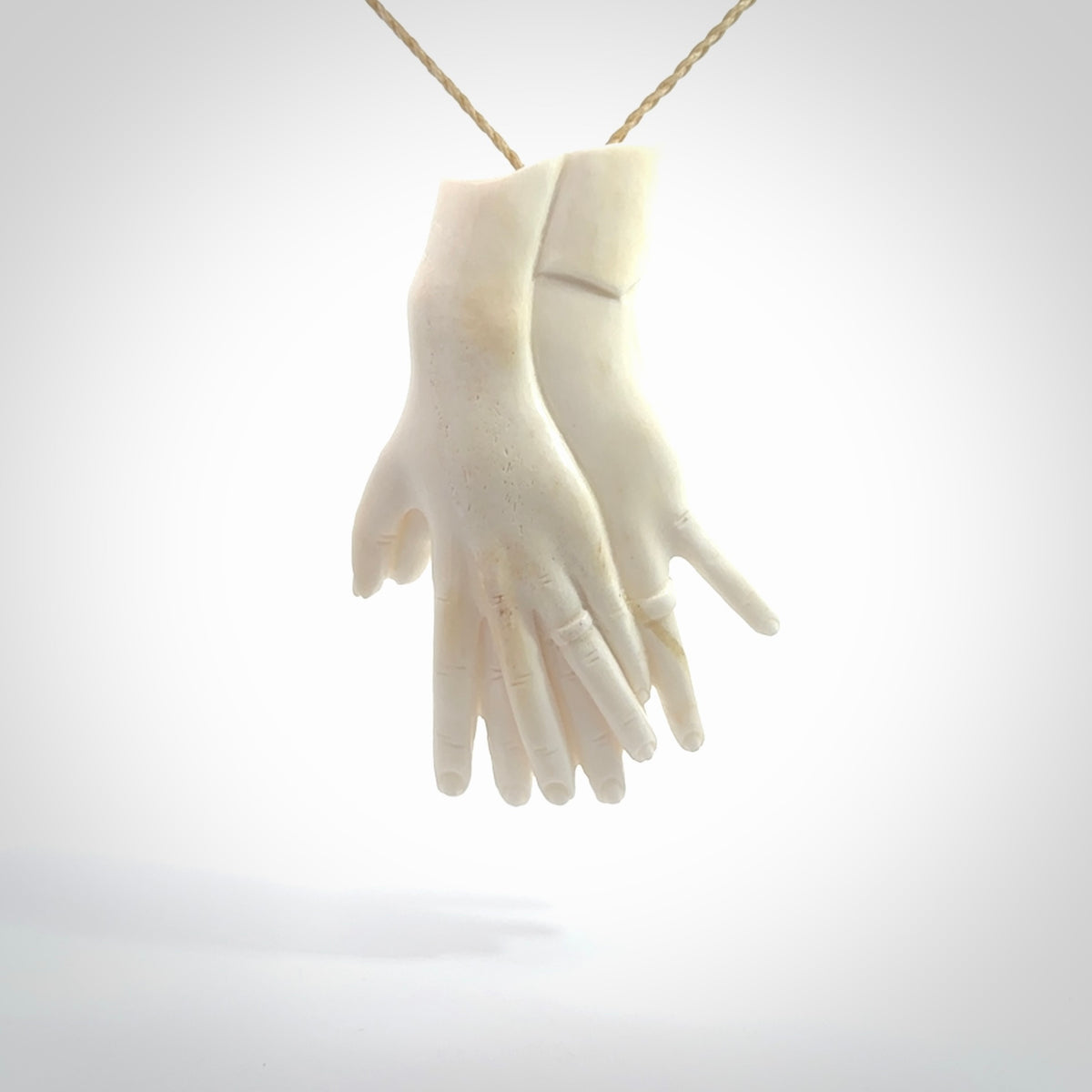 Hand carved large bone double hands with wedding rings pendant. A stunning work of art. This pendant is hand carved in bone and provided with an adjustable cord. A one off work of art to wear by NZ Pacific.