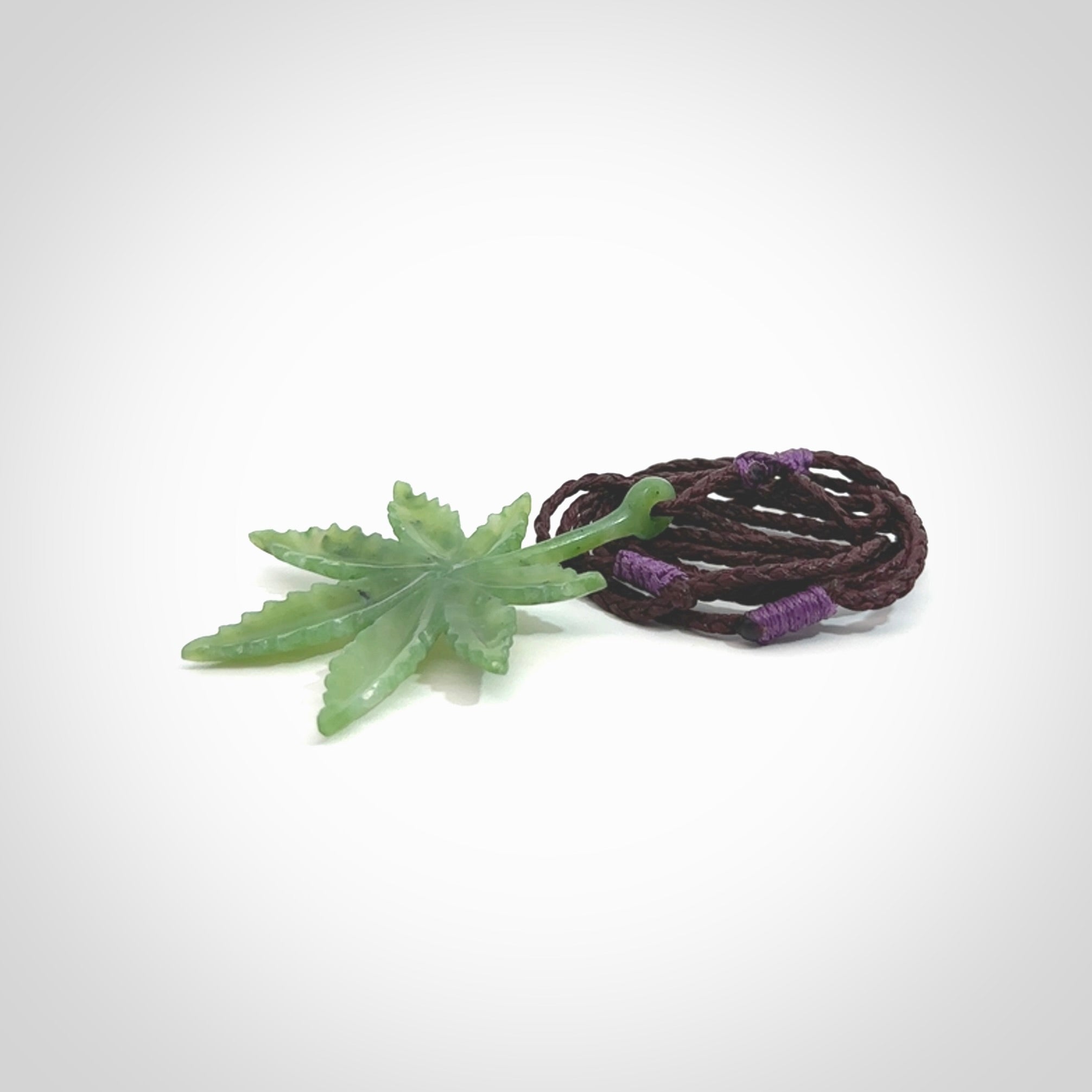 Cannabis Leaf Jade Stone pendant. Handmade jade Cannabis flower jewellery made by NZ Pacific and for sale online. Jade stone Marijuana leaf pendant for men and women. Unique art to wear from NZ Pacific. Delivered on an adjustable Plum cord.