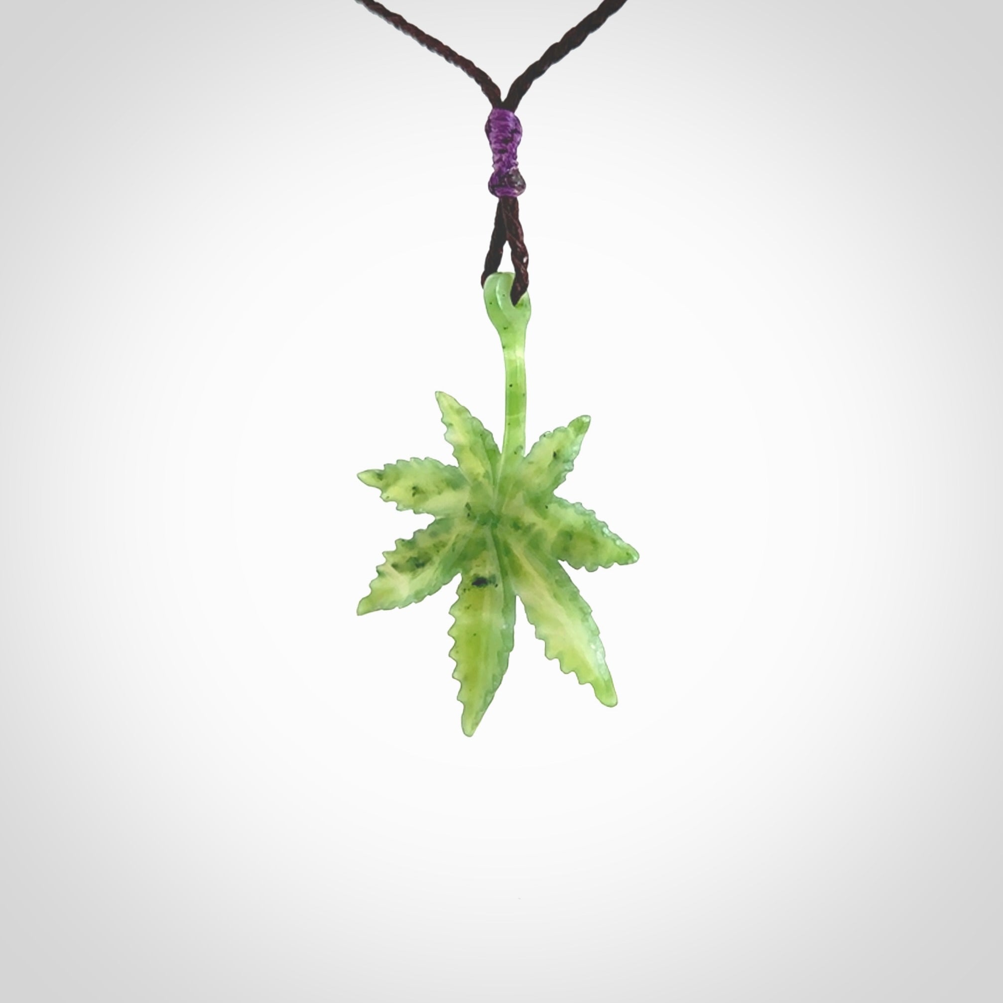 Cannabis Leaf Jade Stone pendant. Handmade jade Cannabis flower jewellery made by NZ Pacific and for sale online. Jade stone Marijuana leaf pendant for men and women. Unique art to wear from NZ Pacific. Delivered on an adjustable Plum cord.