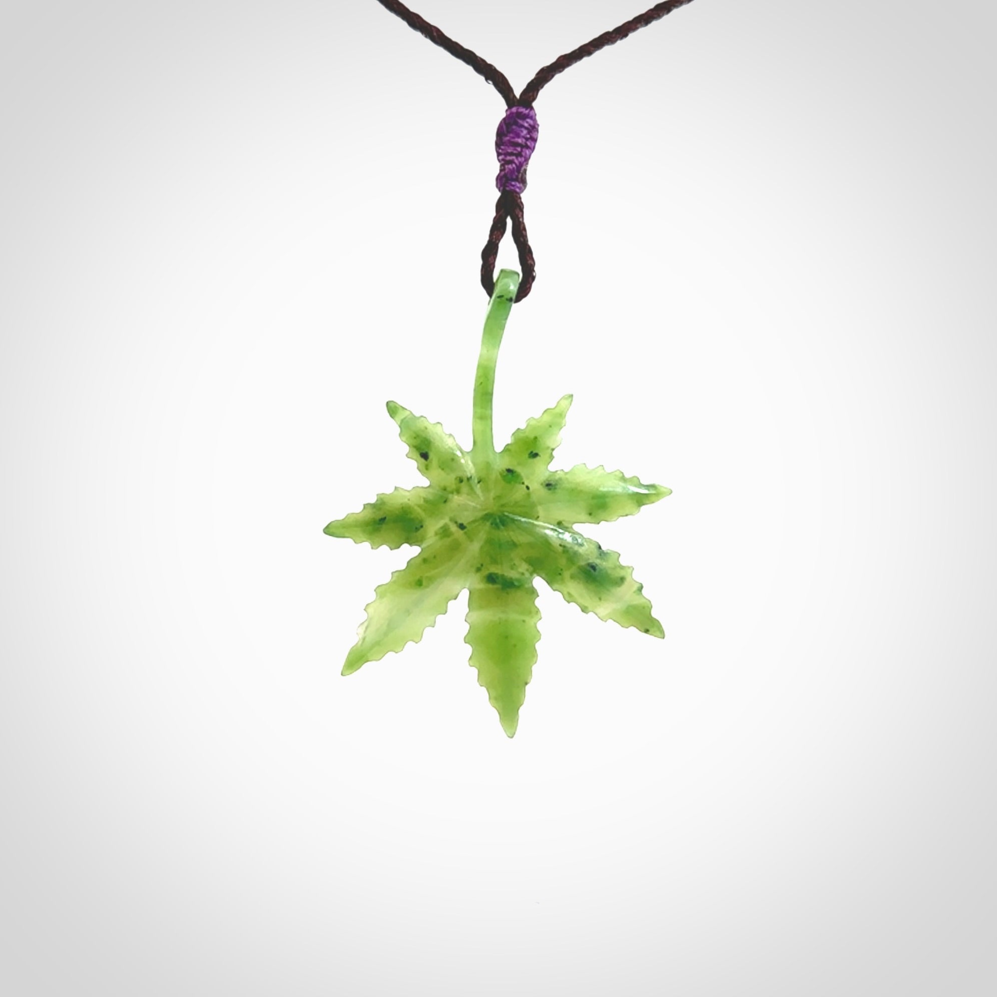 Cannabis Leaf Jade Stone pendant. Handmade jade Cannabis flower jewellery made by NZ Pacific and for sale online. Jade stone Marijuana leaf pendant for men and women. Unique art to wear from NZ Pacific. Delivered on an adjustable Plum cord.