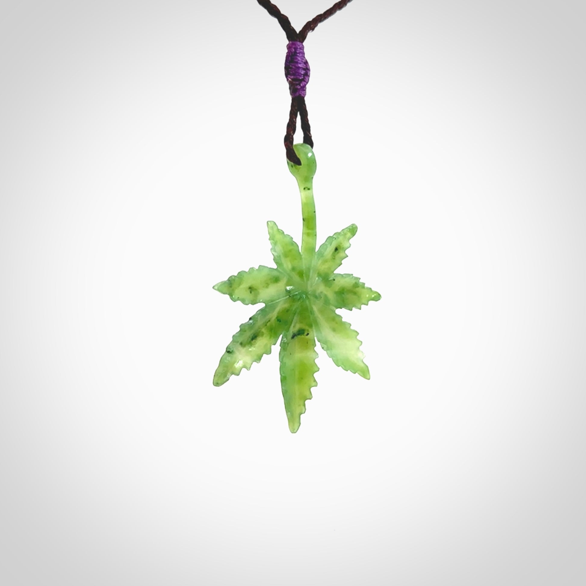 Cannabis Leaf Jade Stone pendant. Handmade jade Cannabis flower jewellery made by NZ Pacific and for sale online. Jade stone Marijuana leaf pendant for men and women. Unique art to wear from NZ Pacific. Delivered on an adjustable Plum cord.