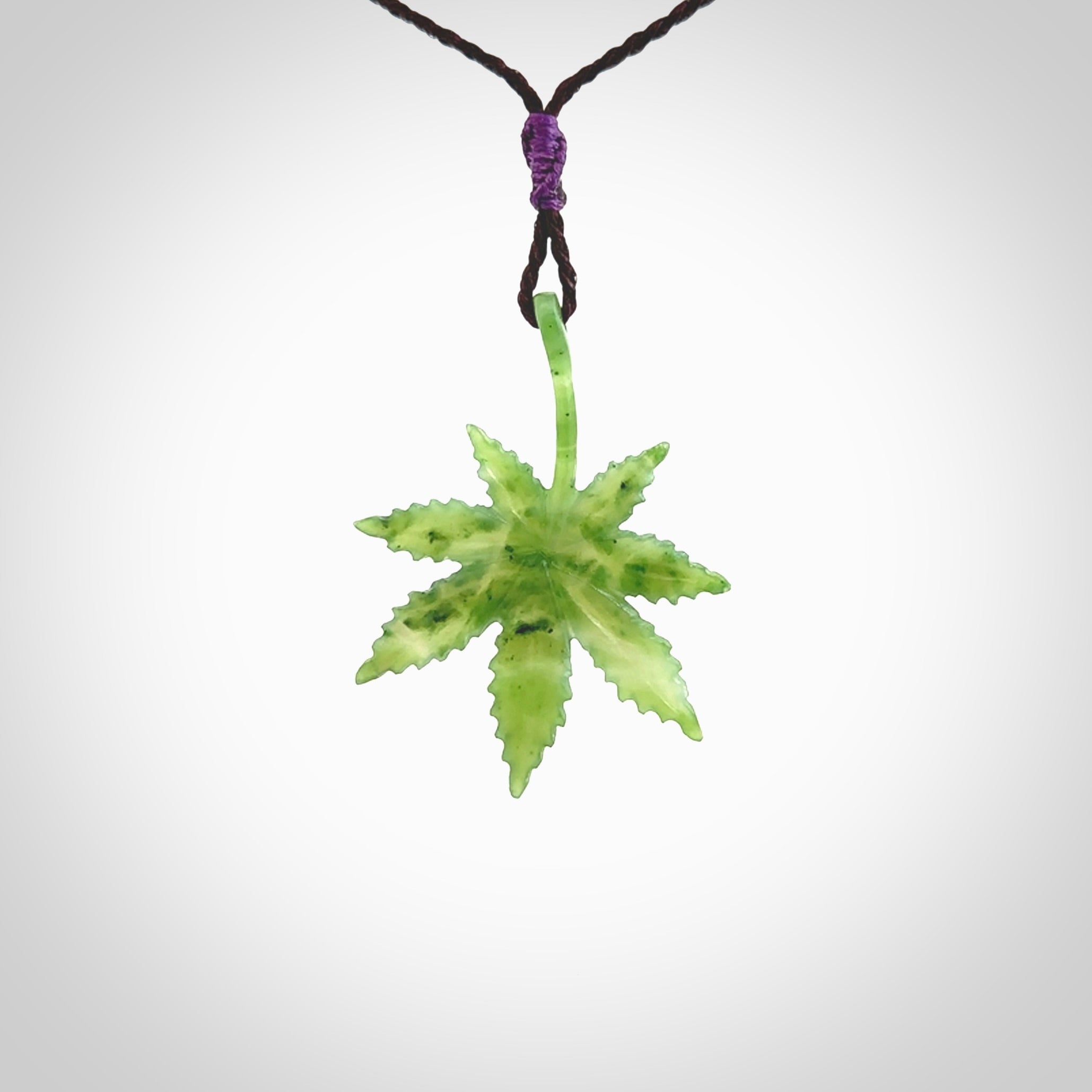 Cannabis Leaf Jade Stone pendant. Handmade jade Cannabis flower jewellery made by NZ Pacific and for sale online. Jade stone Marijuana leaf pendant for men and women. Unique art to wear from NZ Pacific. Delivered on an adjustable Plum cord.