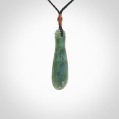 This is a sleek and slender hand carved New Zealand Jade mere pendant. The stone is a very beautiful green and the cord is either black or green and is adjustable. The pendant has a light polish and just glows. Provided in a woven kete pouch.