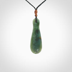 This is a sleek and slender hand carved New Zealand Jade mere pendant. The stone is a very beautiful green and the cord is either black or green and is adjustable. The pendant has a light polish and just glows. Provided in a woven kete pouch.