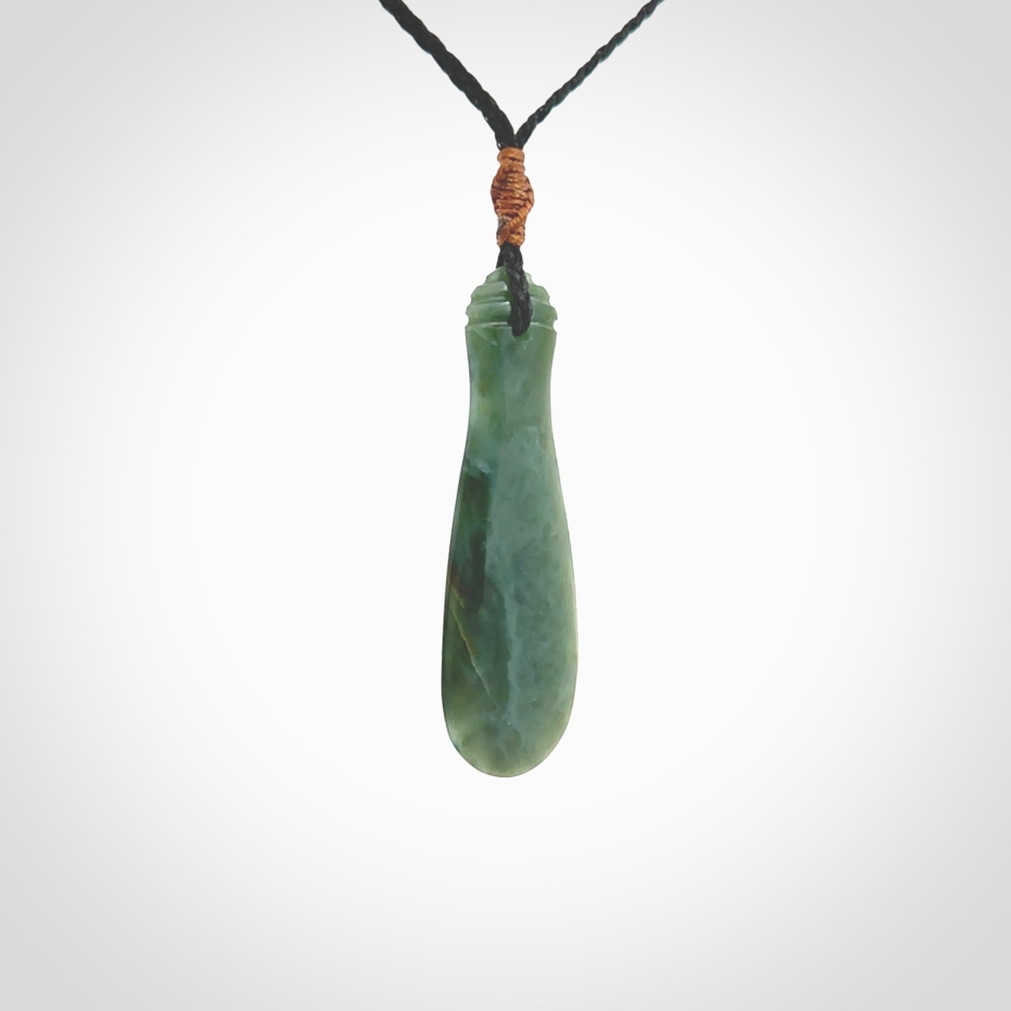 This is a sleek and slender hand carved New Zealand Jade mere pendant. The stone is a very beautiful green and the cord is either black or green and is adjustable. The pendant has a light polish and just glows. Provided in a woven kete pouch.