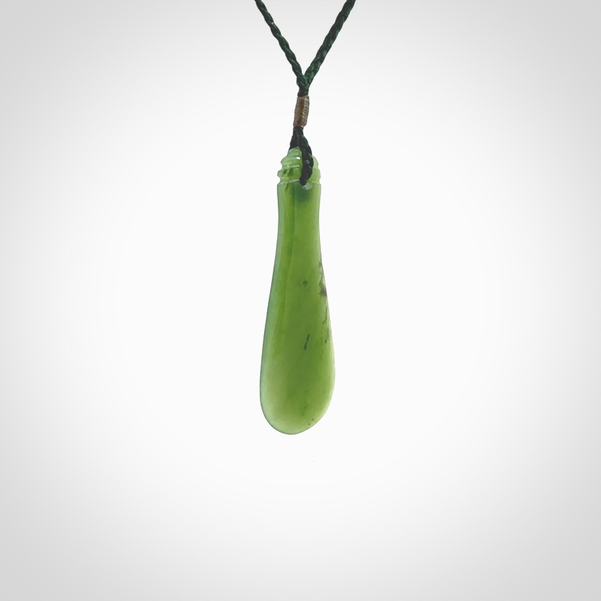 This is a sleek and slender hand carved New Zealand Jade mere pendant. The stone is a very beautiful green and the cord is either black or green and is adjustable. The pendant has a light polish and just glows. Provided in a woven kete pouch.