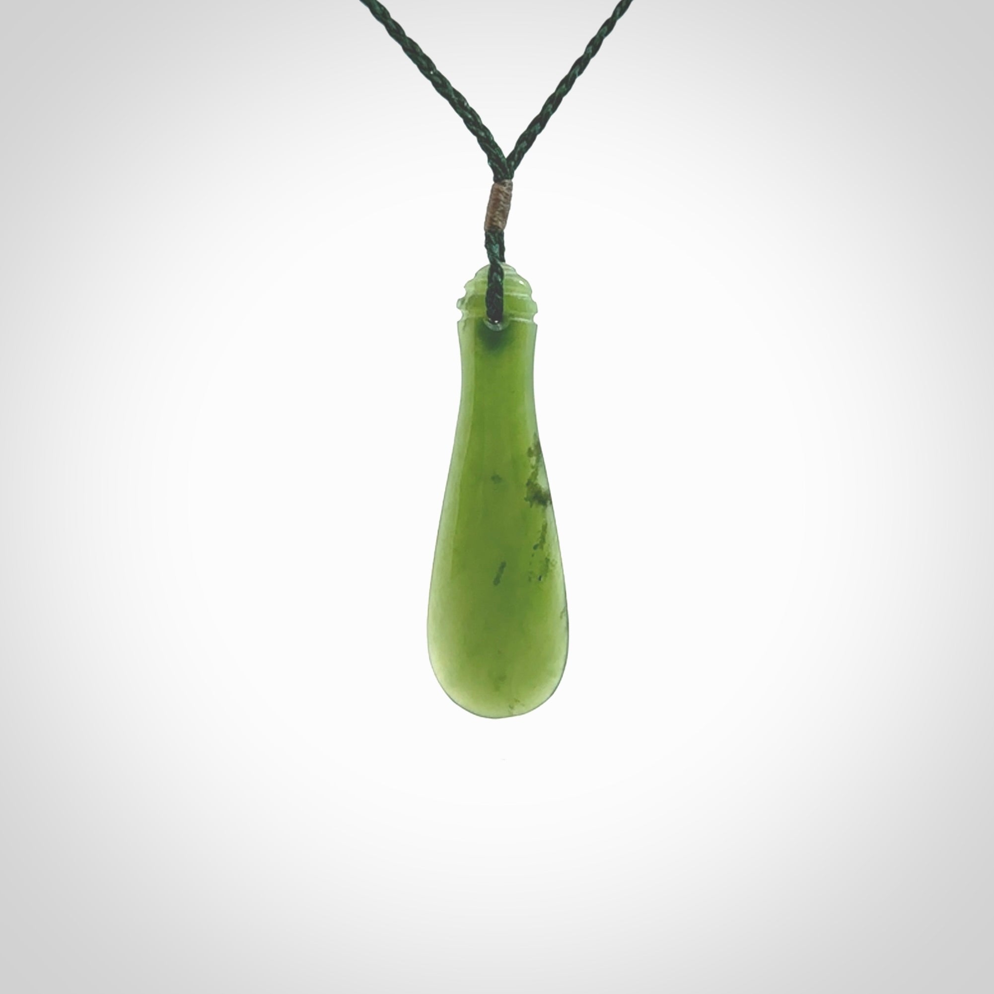 This is a sleek and slender hand carved New Zealand Jade mere pendant. The stone is a very beautiful green and the cord is either black or green and is adjustable. The pendant has a light polish and just glows. Provided in a woven kete pouch.